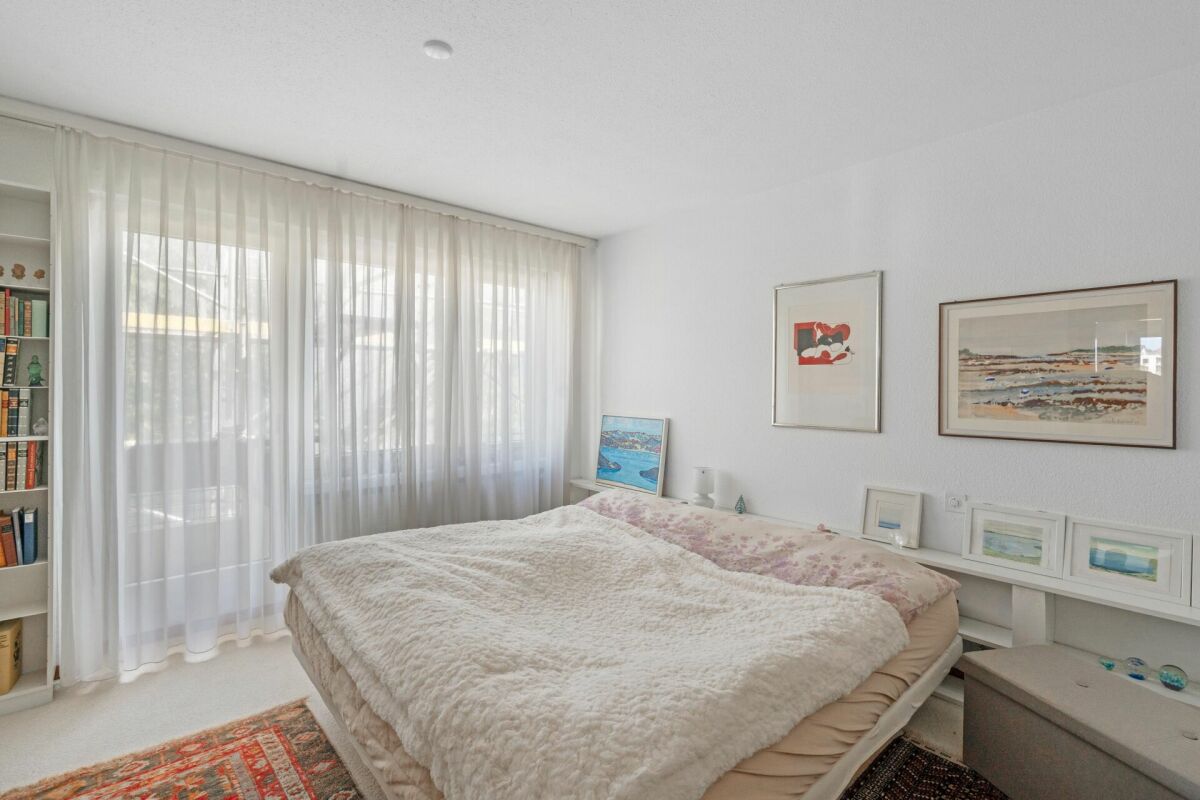 Helles Schlafzimmer mit großer Fensterfront und Bett