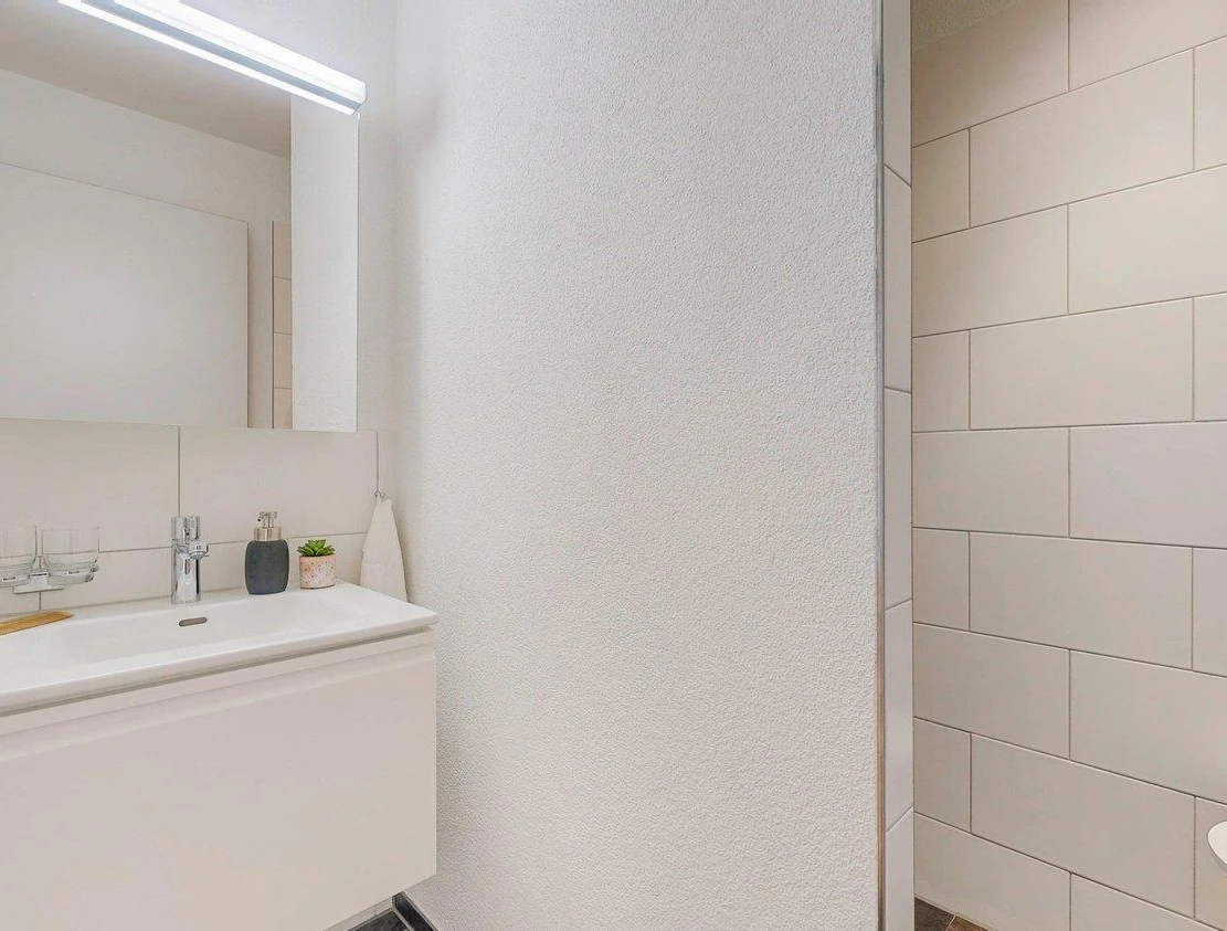 Modernes Gäste-Bad mit Waschtisch und Teilblick auf die Dusche