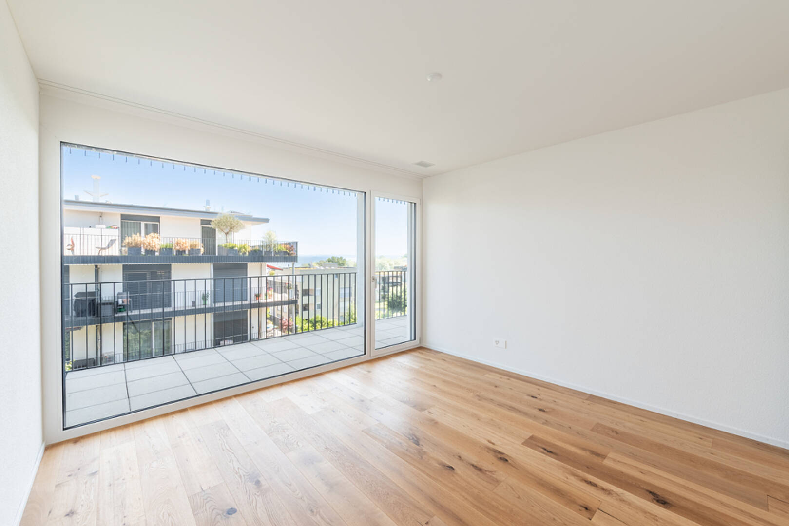 Heller leerer Wohnraum mit großem Balkon und Ausblick