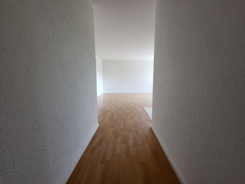 Leerer Flur mit Blick in einen hellen Wohnbereich