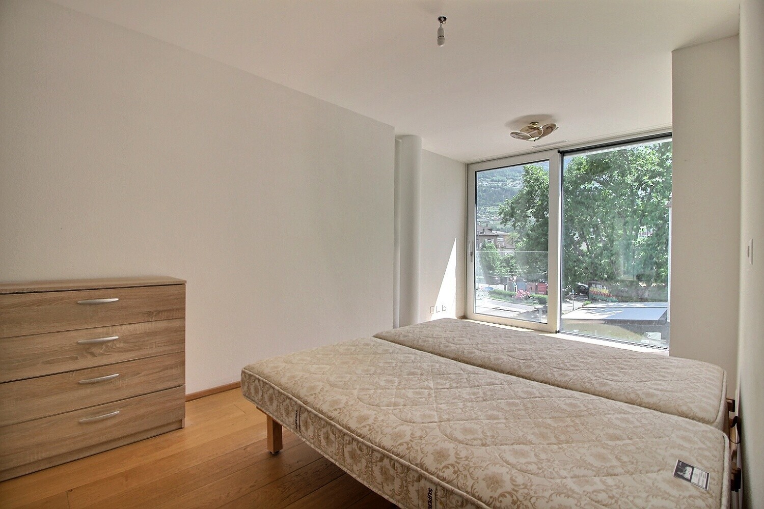 Helles Schlafzimmer mit zwei Matratzen und großem Fenster