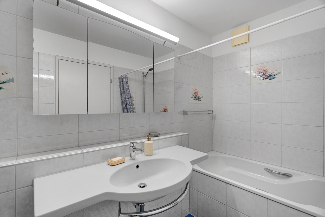 Helles Badezimmer mit Wannenbereich und Waschtisch