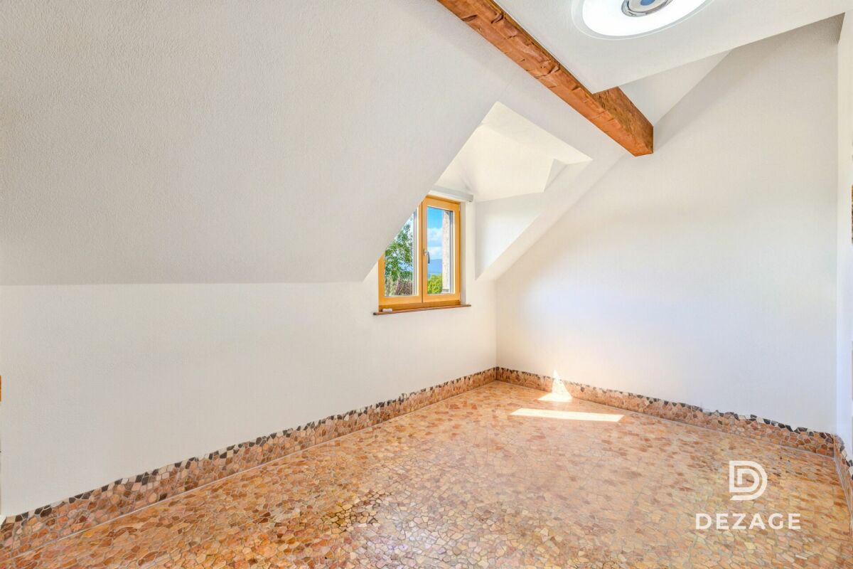 Dachgeschosszimmer mit Holzfenster und Natursteinboden
