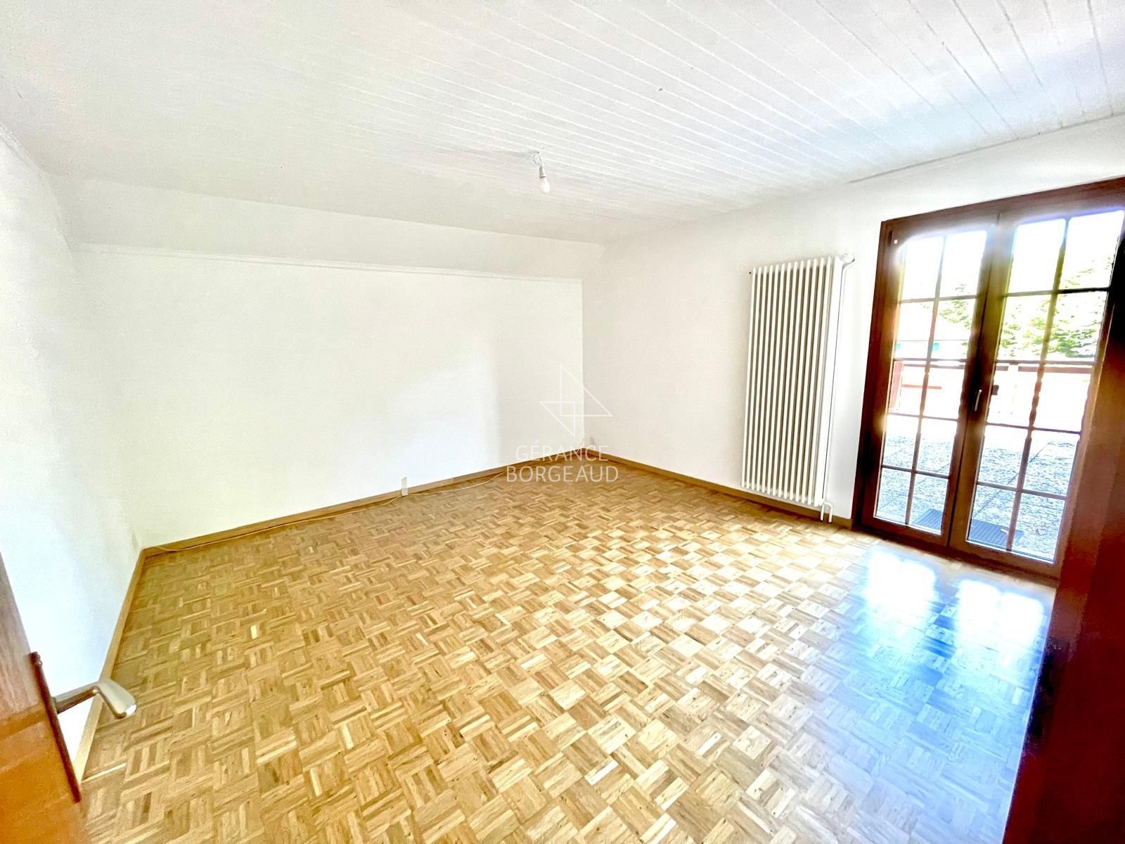 Heller leerer Raum mit Holzboden und Balkontür