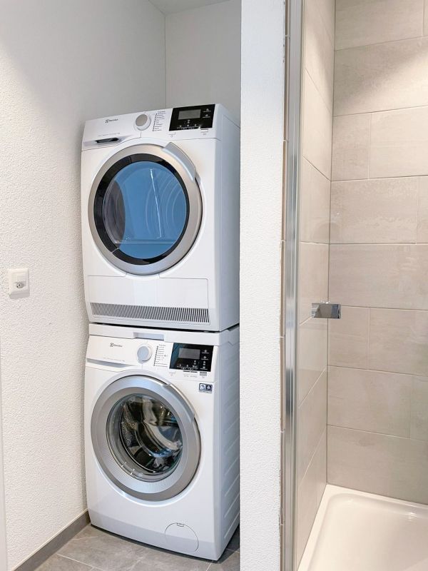 Hauswirtschaftsbereich mit gestapeltem Waschtrockner neben der Dusche