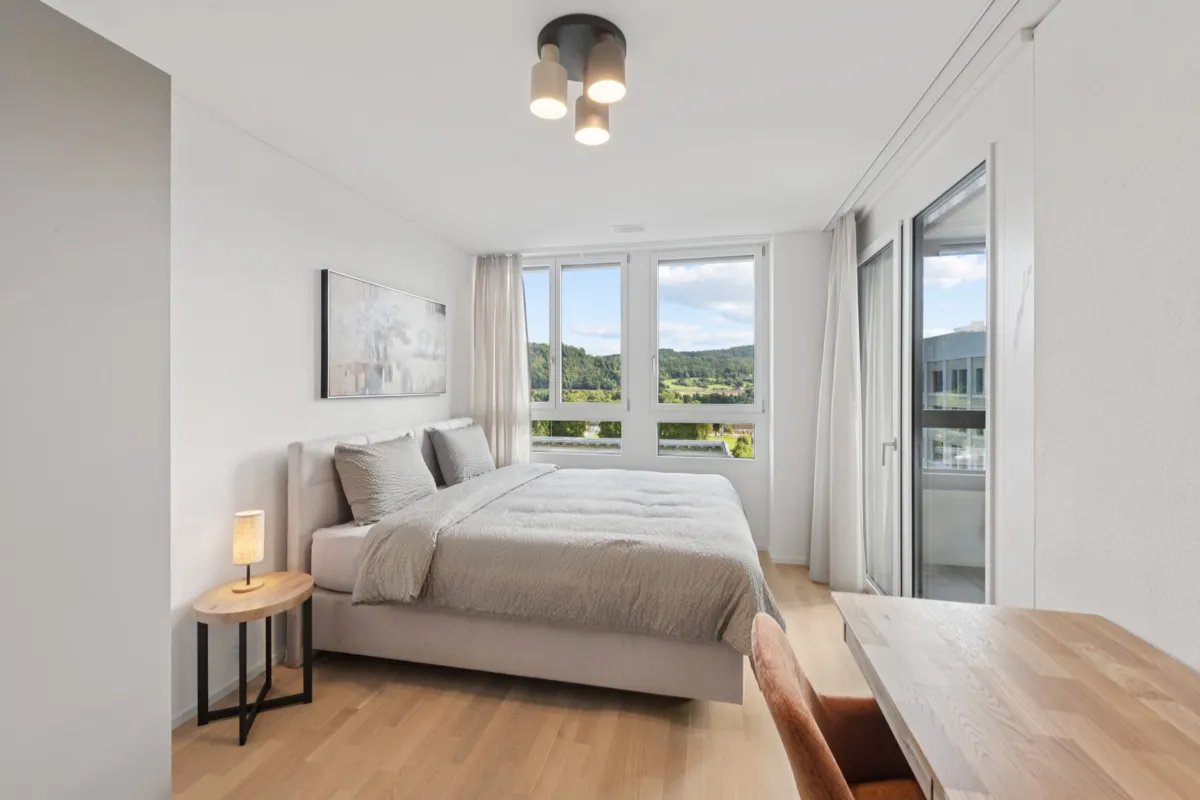 Schlafzimmer mit großem Fenster und Balkonblick