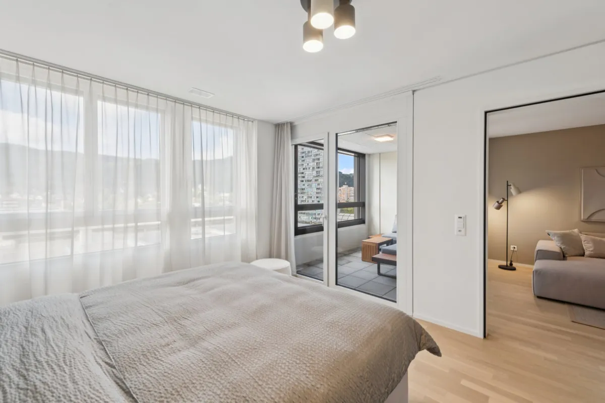Helles Schlafzimmer mit Blick auf Balkon und angrenzenden Wohnbereich