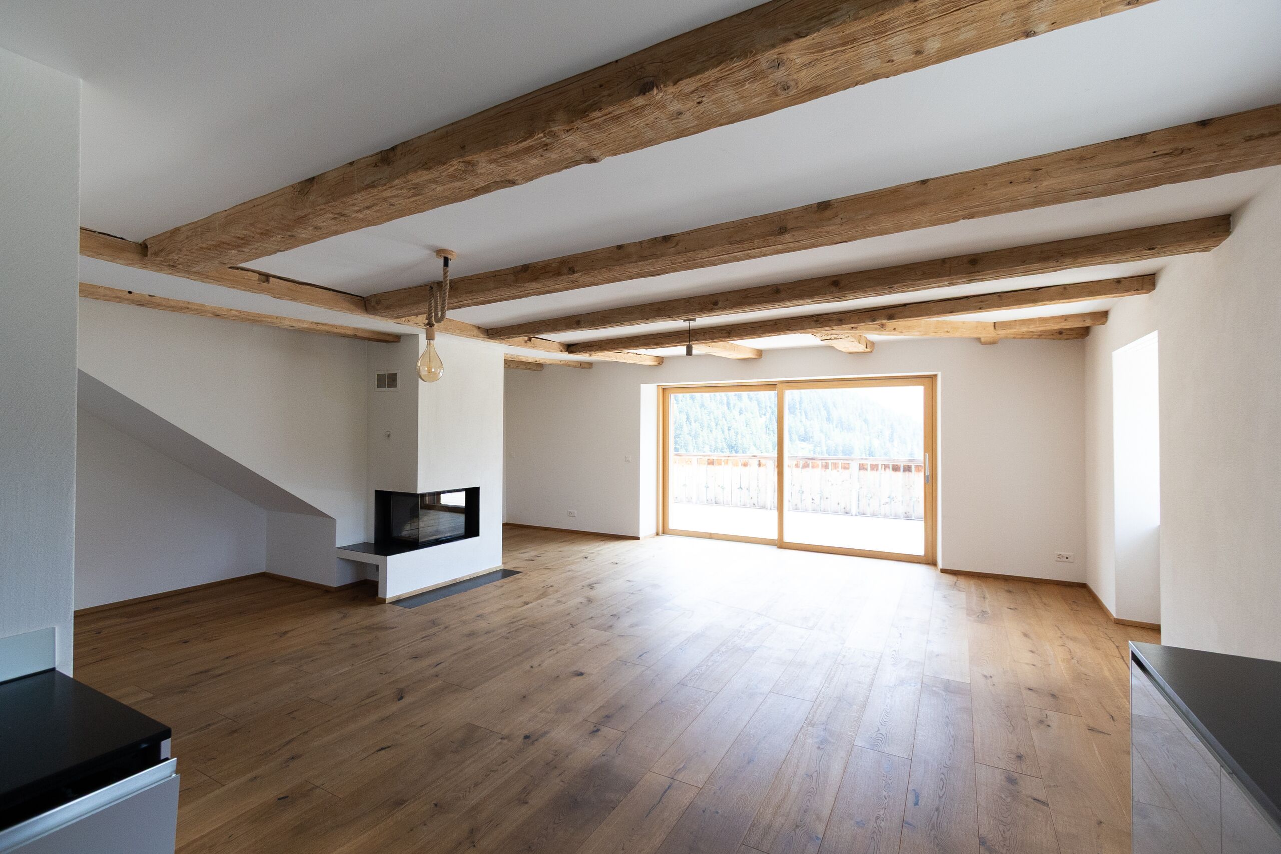 Großer Wohnraum mit Holzbalken und Balkonblick