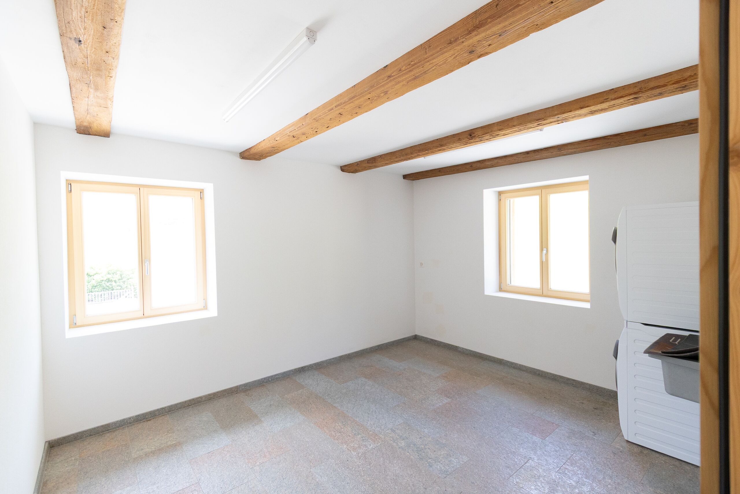 Heller leerer Raum mit Holzbalken und Fenstern