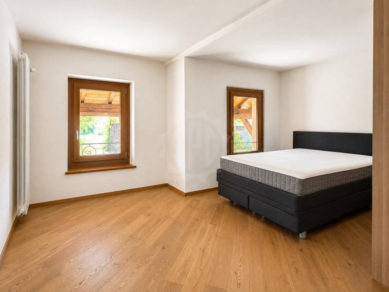 Schlafzimmer mit Holzboden und zwei Fenstern