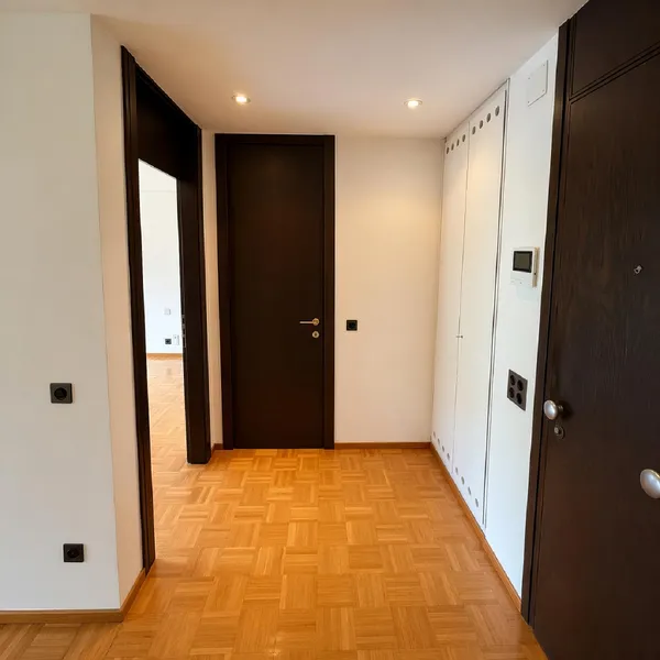 Heller Flur mit Holzboden und dunklen Türen