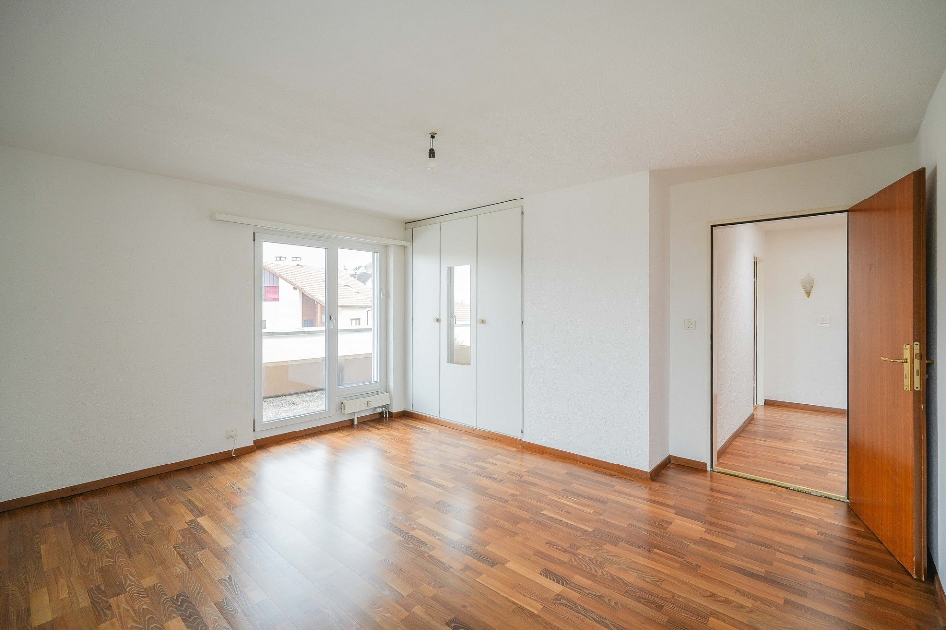 Leerer Wohnraum mit Balkonfenster und Einbauschrank
