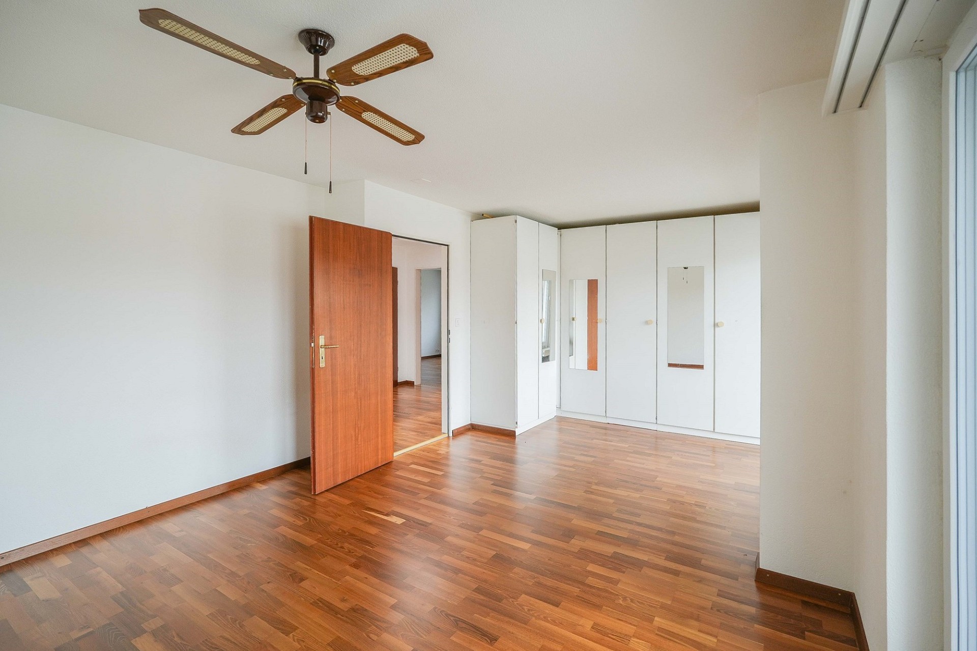 Helles Schlafzimmer mit Holzfußboden und Einbauschränken