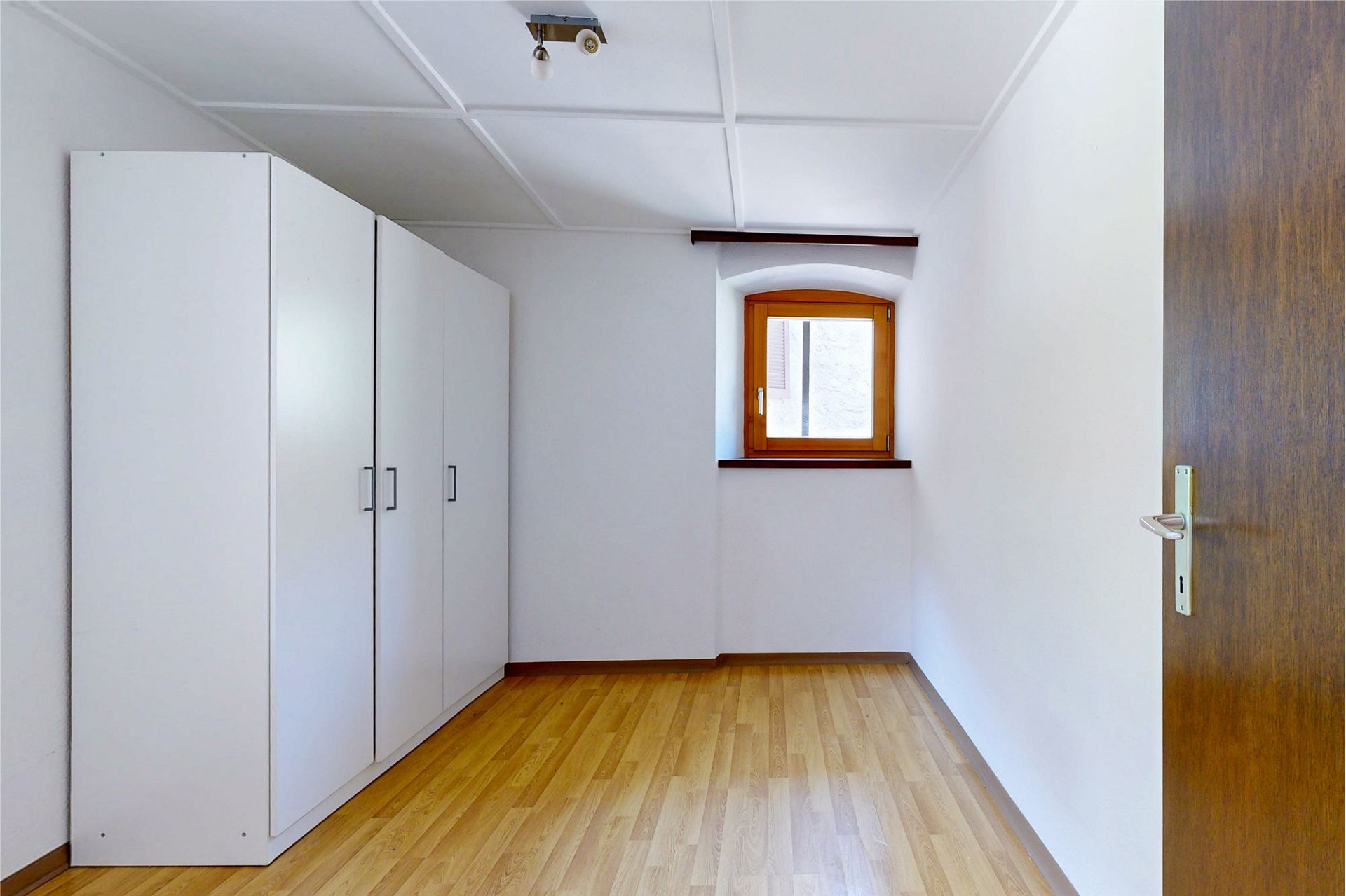 Helles Zimmer mit Einbauschrank und Holzfenster