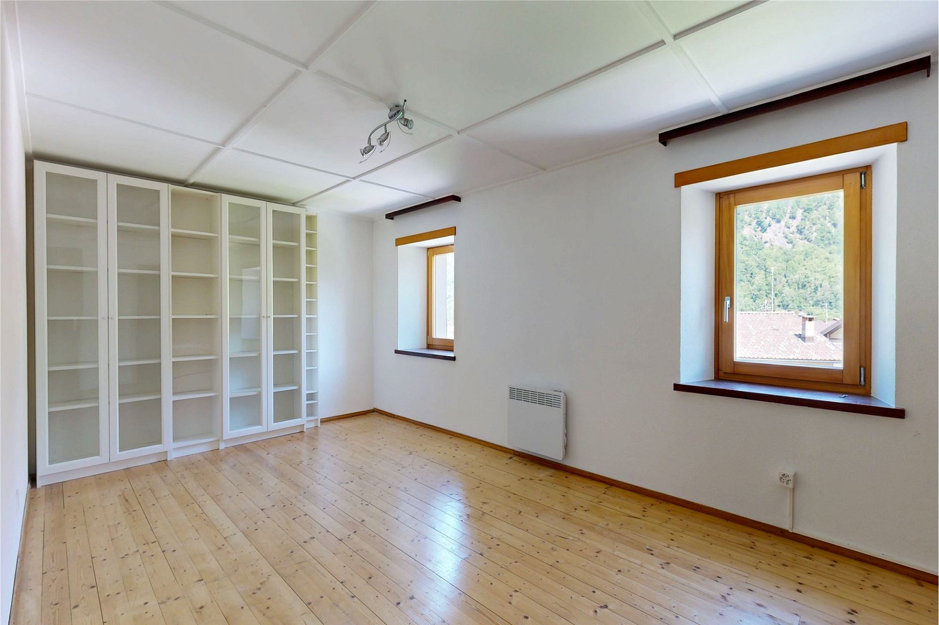 Helles, leeres Zimmer mit Einbauschränken und Holzfenstern
