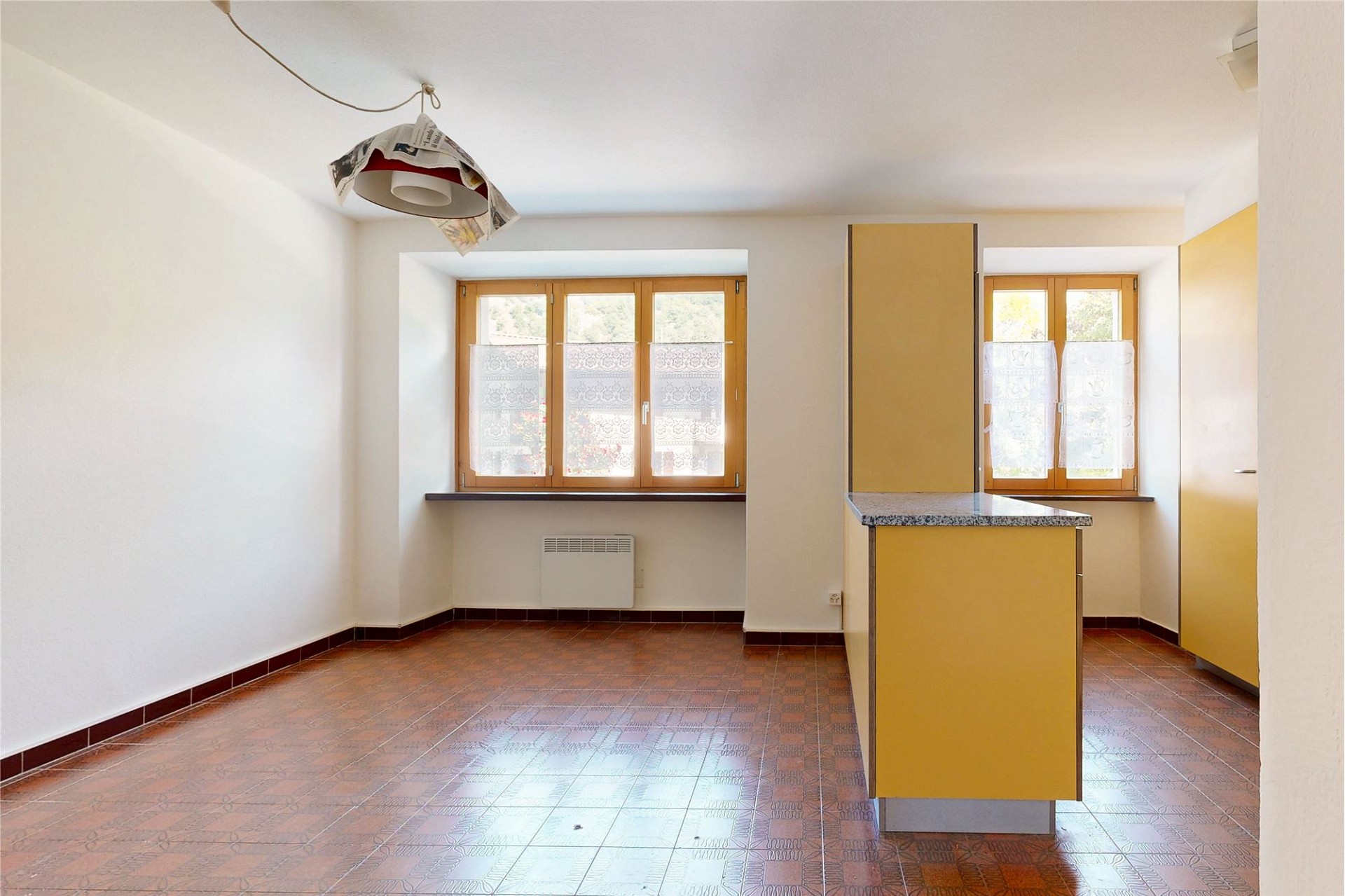 Heller leerer Raum mit Terrakottafliesen und gelben Einbauten