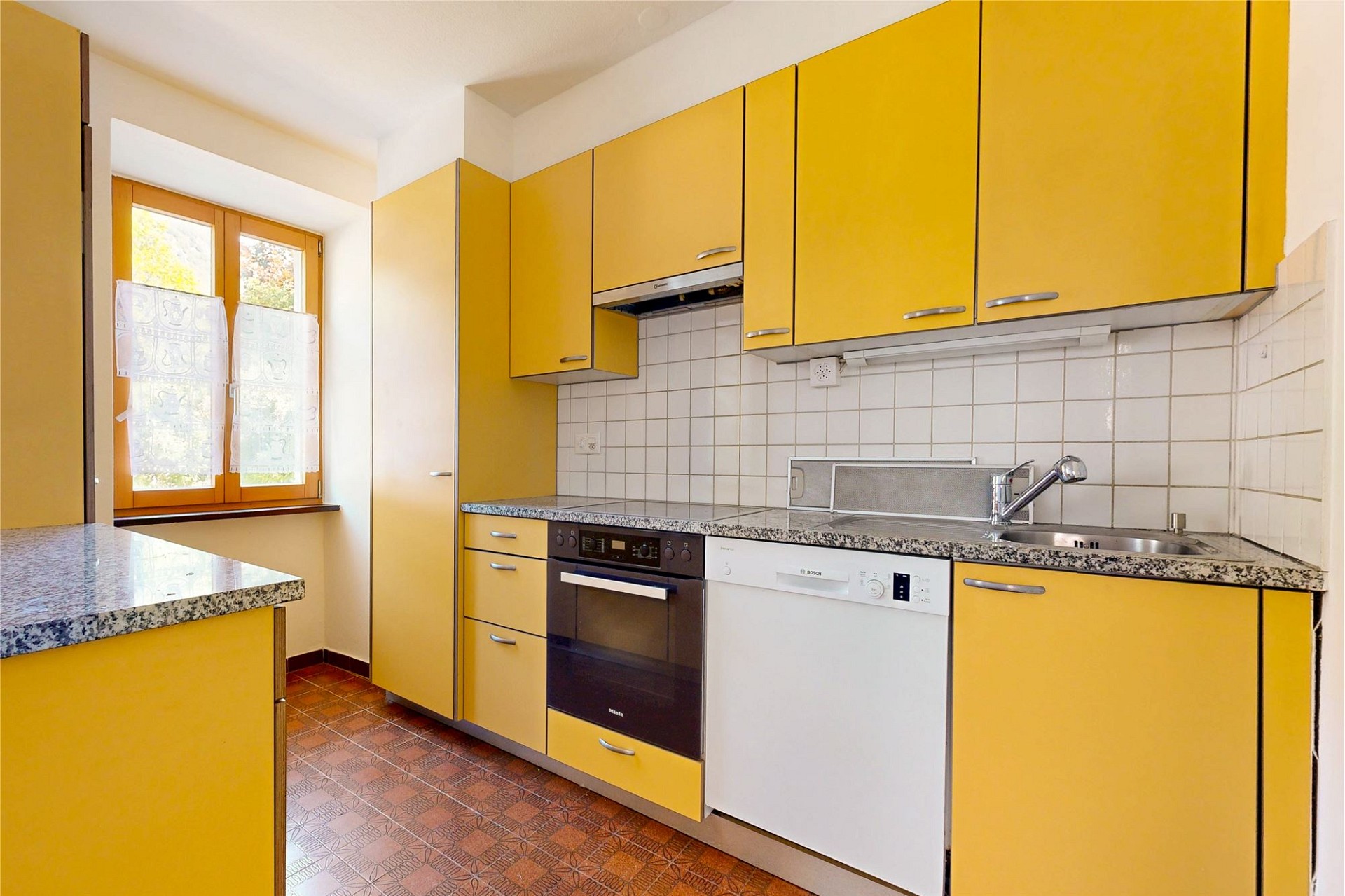 Gelbe Küche mit Fenster und Einbaugeräten
