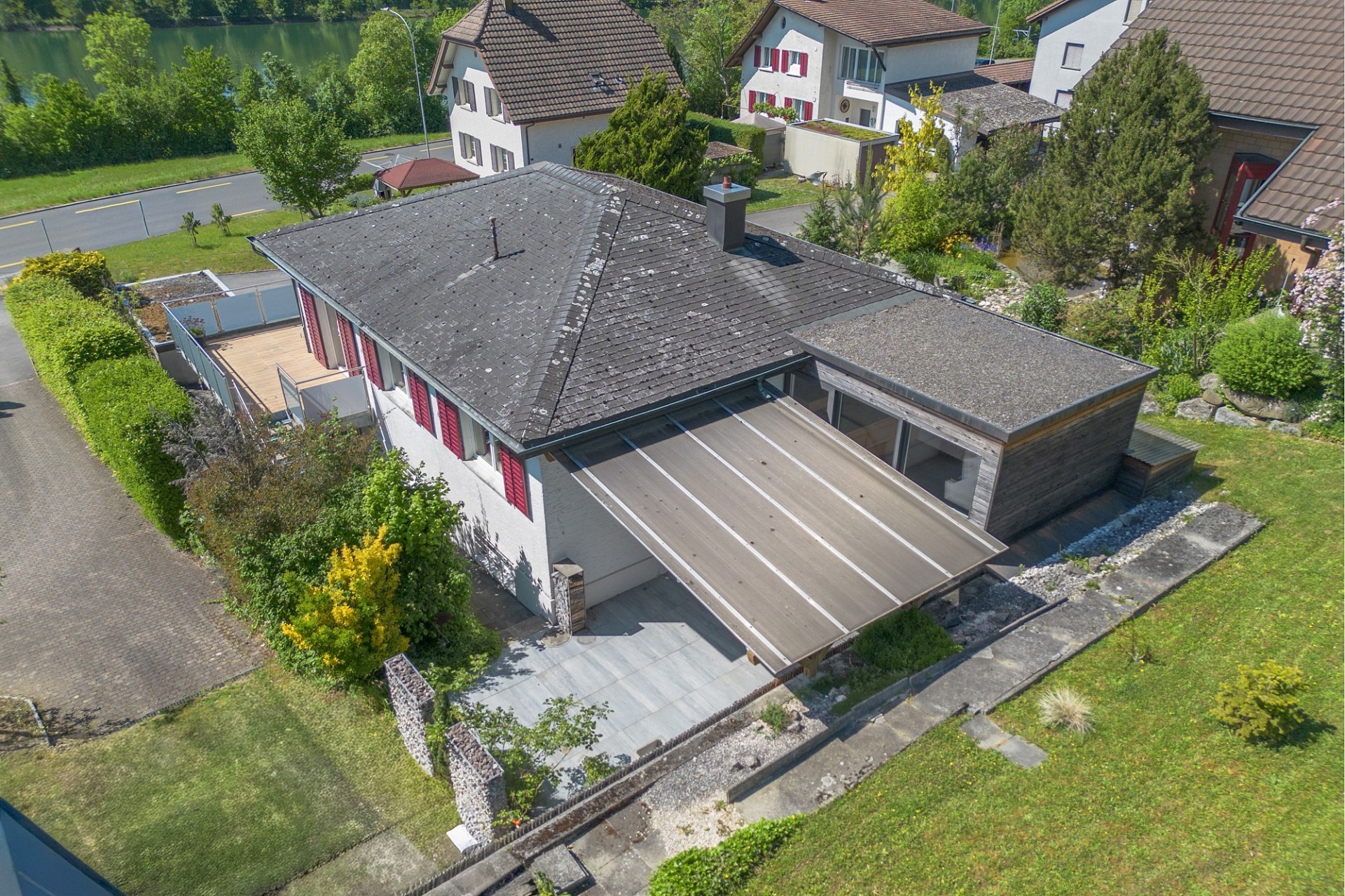 Drohnenansicht eines Einfamilienhauses mit Garten und Umgebung am Wasser