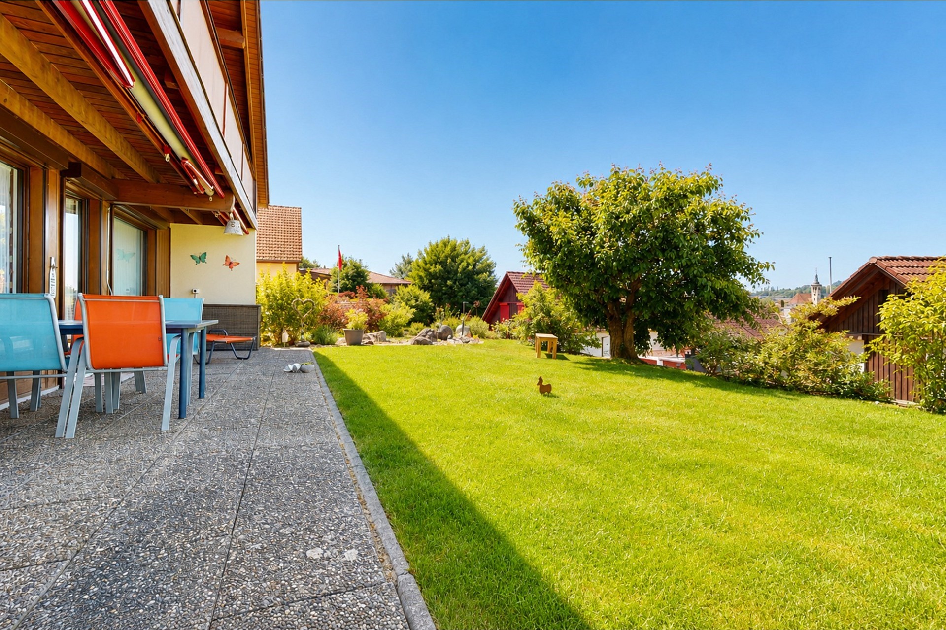 Sonnige Garten- und Terrassenansicht eines Wohnhauses