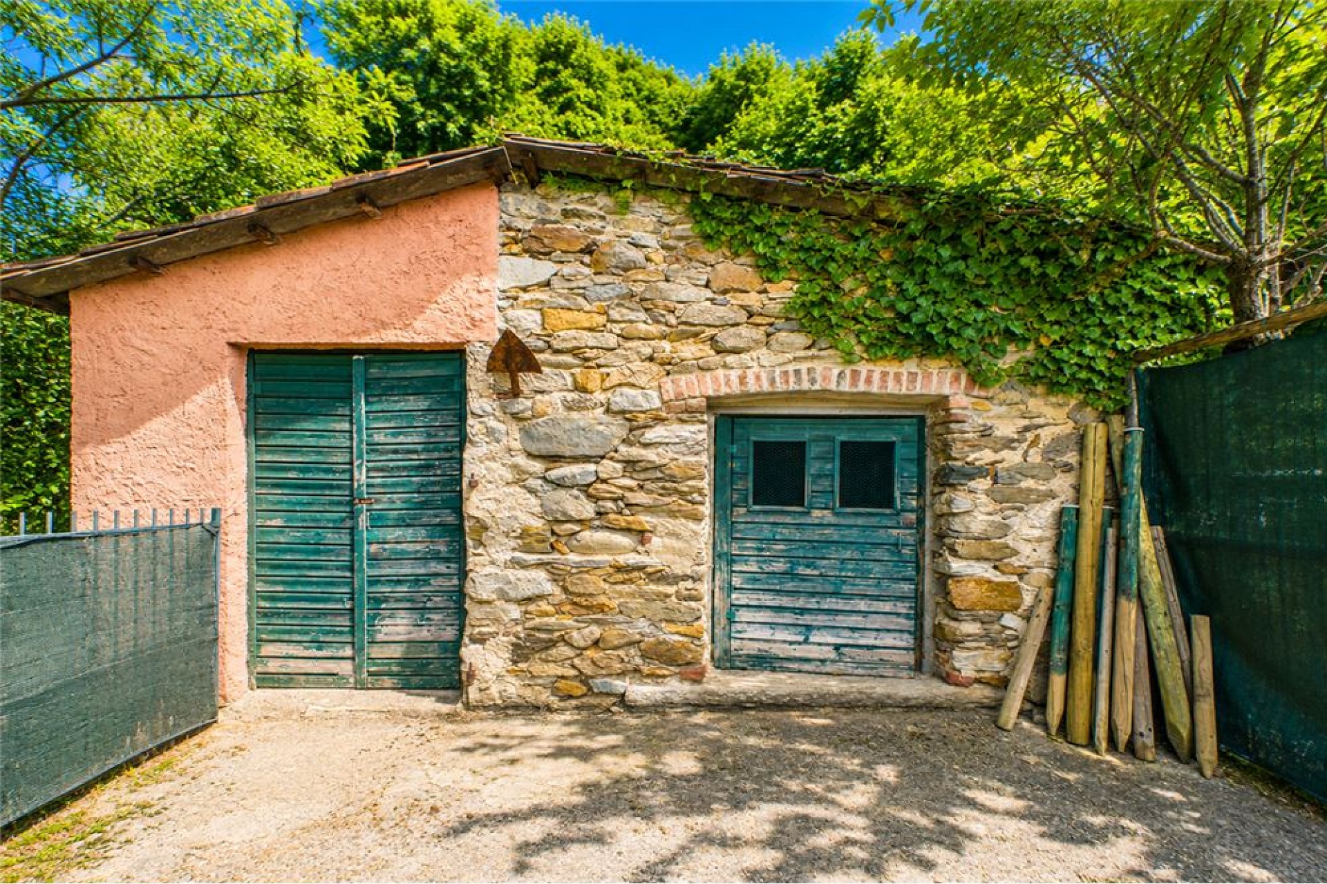 Rustikale Steinhütte mit grünen Holzläden