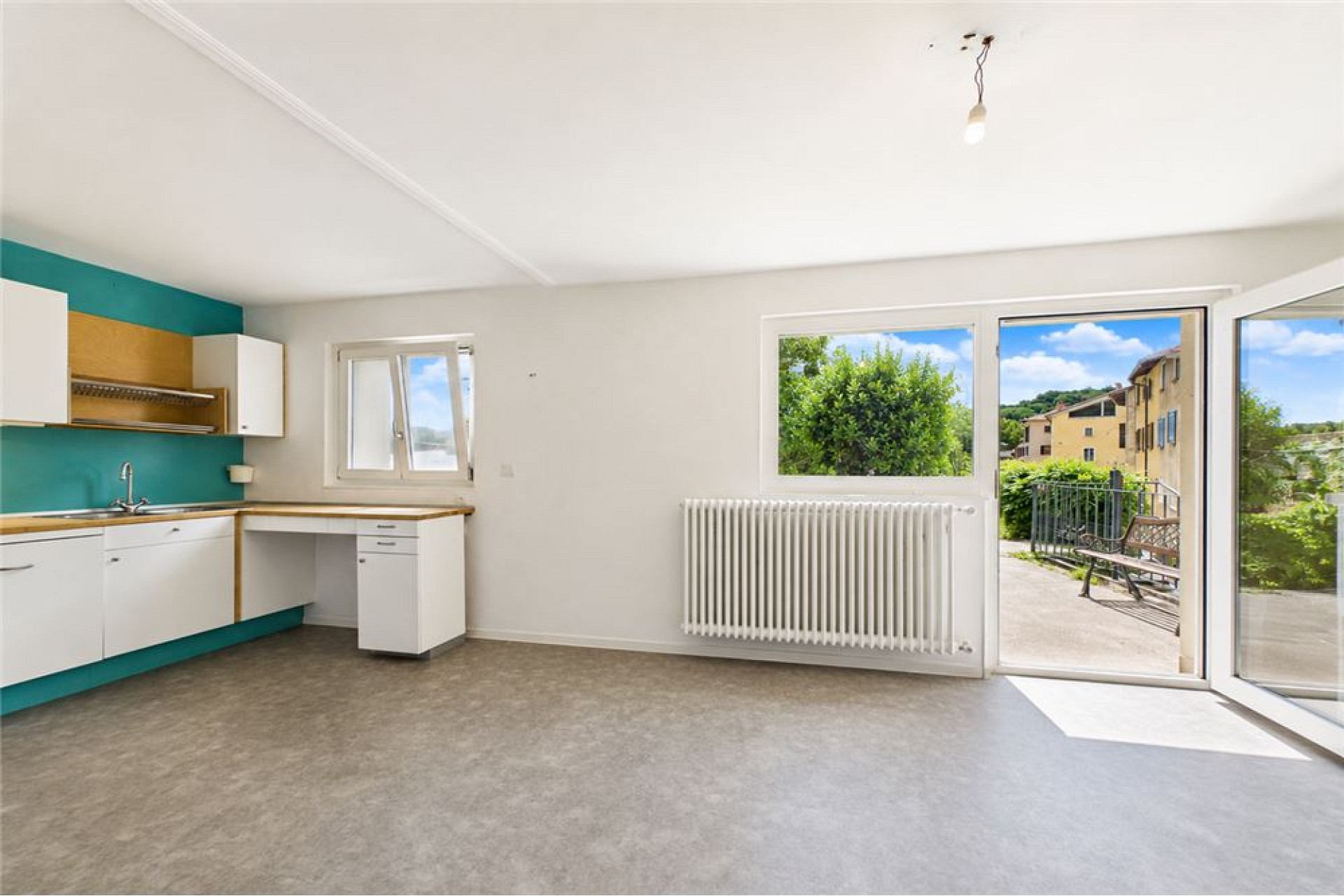 Helles Wohnzimmer mit Küchenzeile und Terrassentüren