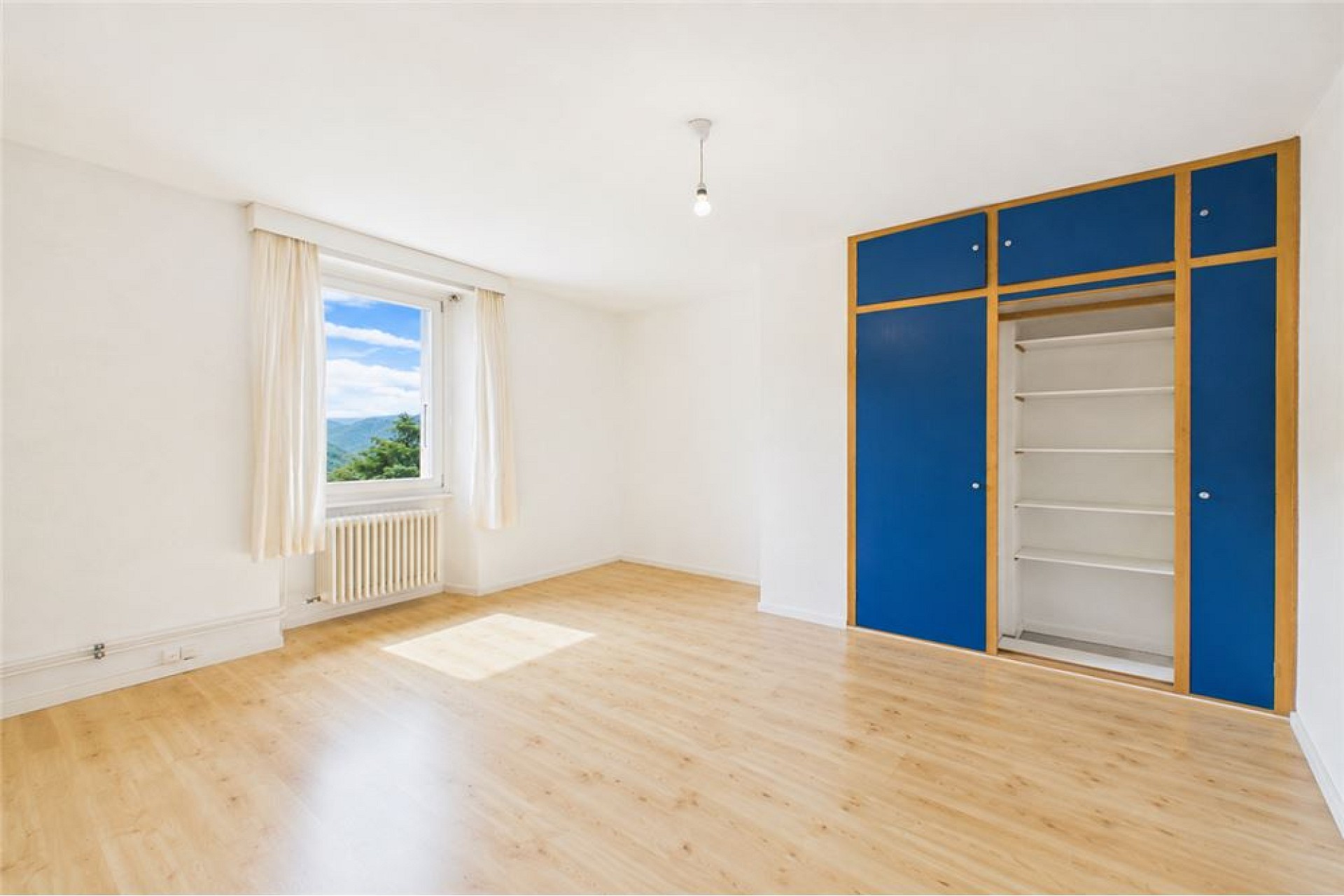 Helles Schlafzimmer mit großem Fenster und Einbauschrank
