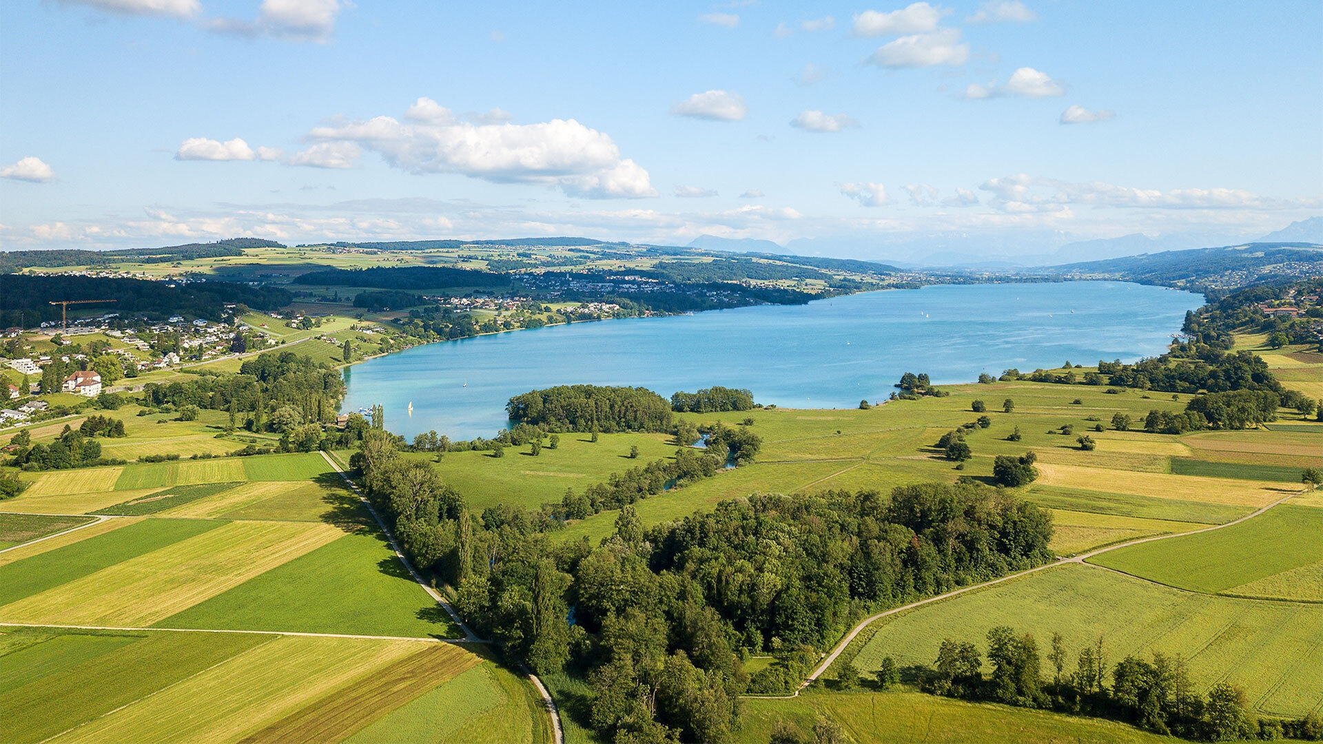 Landschaftsaufnahme mit See und Feldern