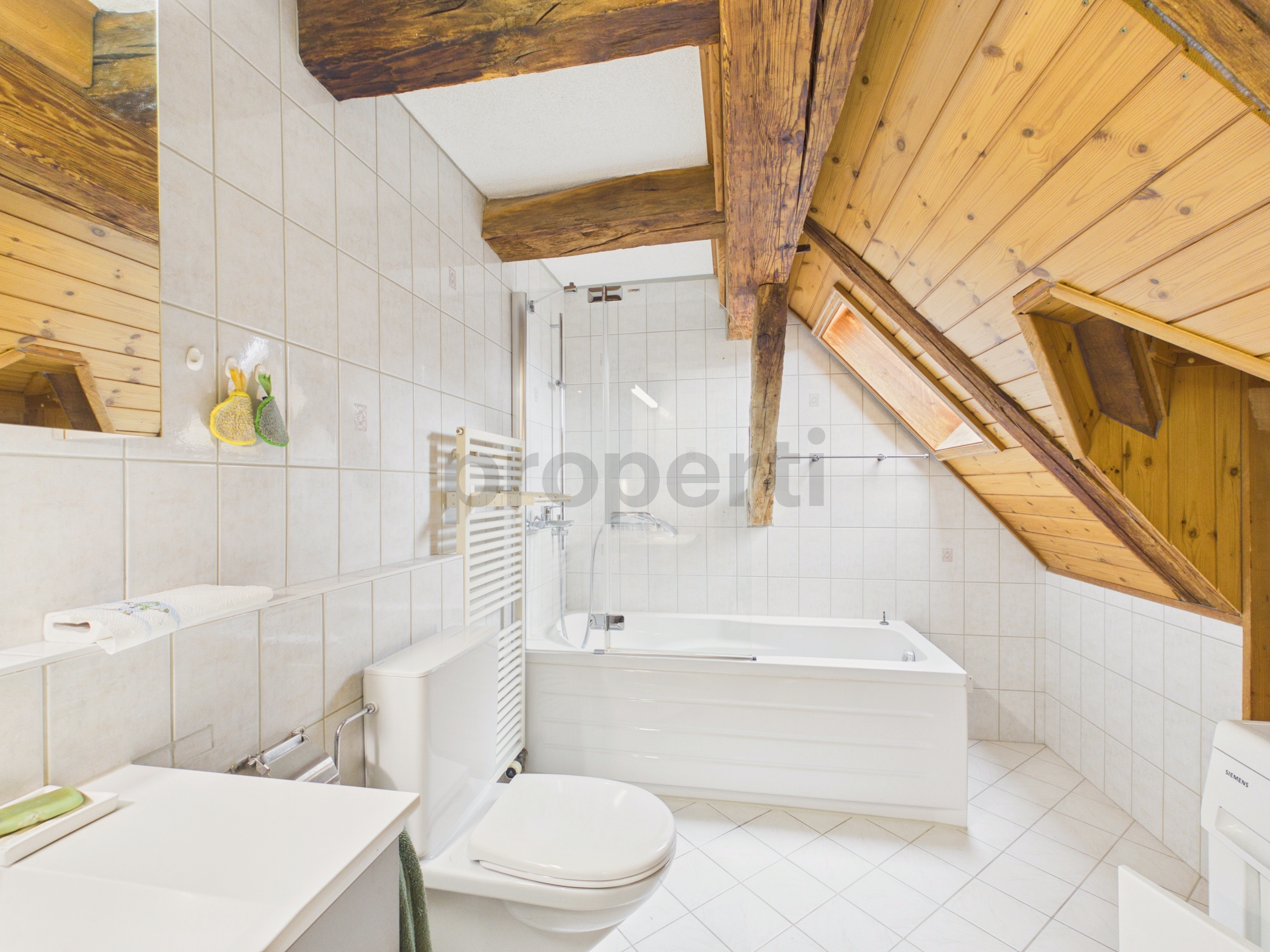 Dachgeschossbad mit Badewanne und Holzdecke