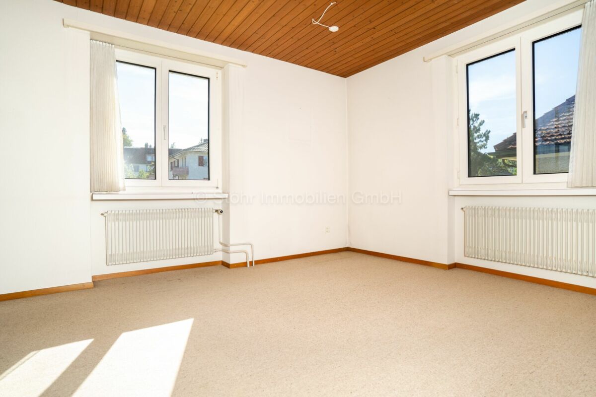 Leeres Zimmer mit Holzdecke und zwei Fenstern