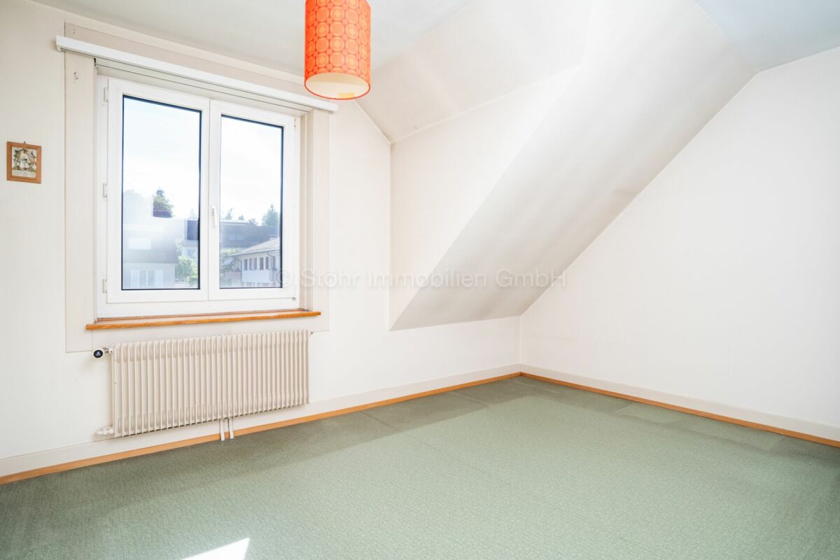 Dachgeschosszimmer mit Fenster und Heizkörper