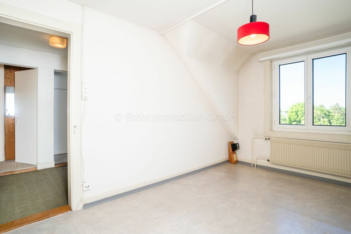Helles Dachzimmer mit Fenster und Heizkörper