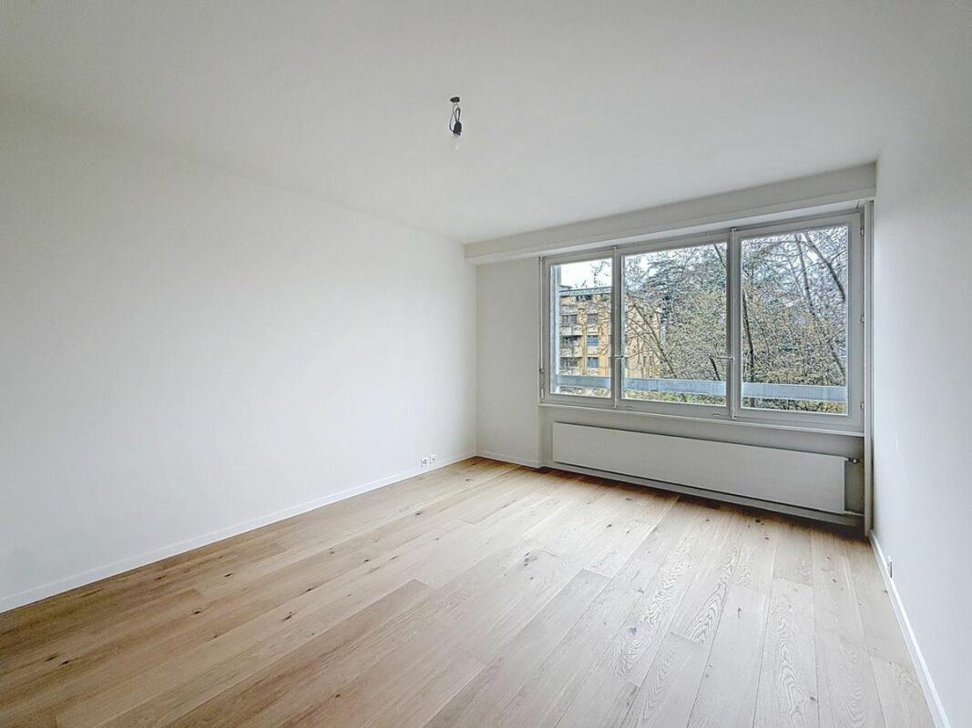 Heller leerer Raum mit großem Fenster und Holzfußboden