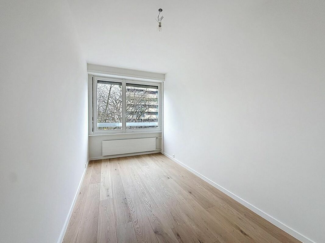 Helles, leeres Zimmer mit Fenster und Parkettboden