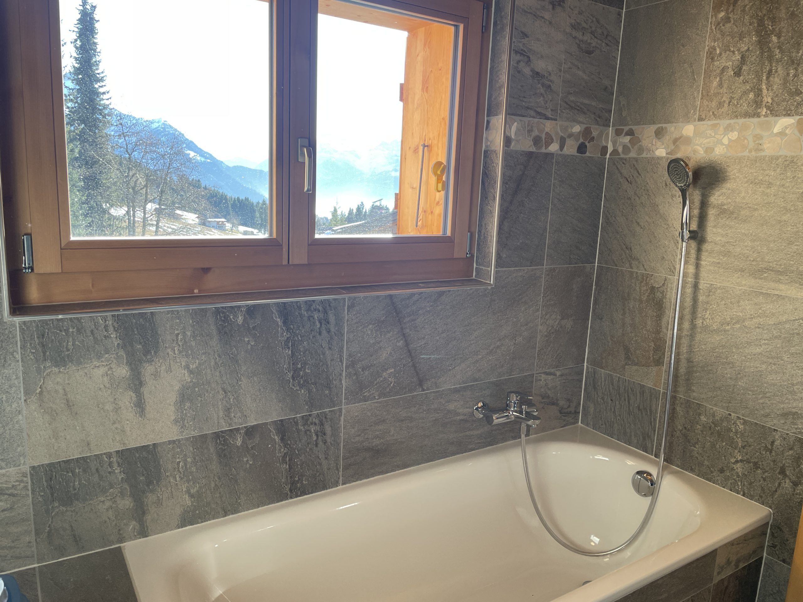 Badezimmer mit Badewanne und Bergblick