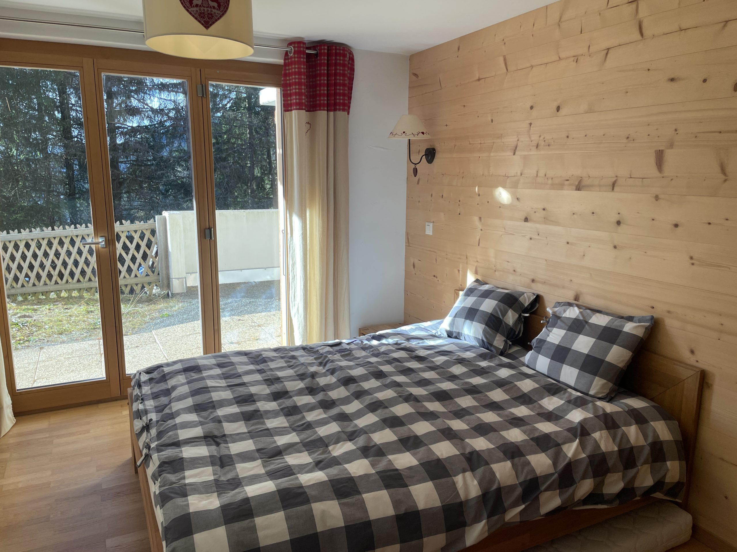 Gemütliches Schlafzimmer mit Holzwand und Terrassentür