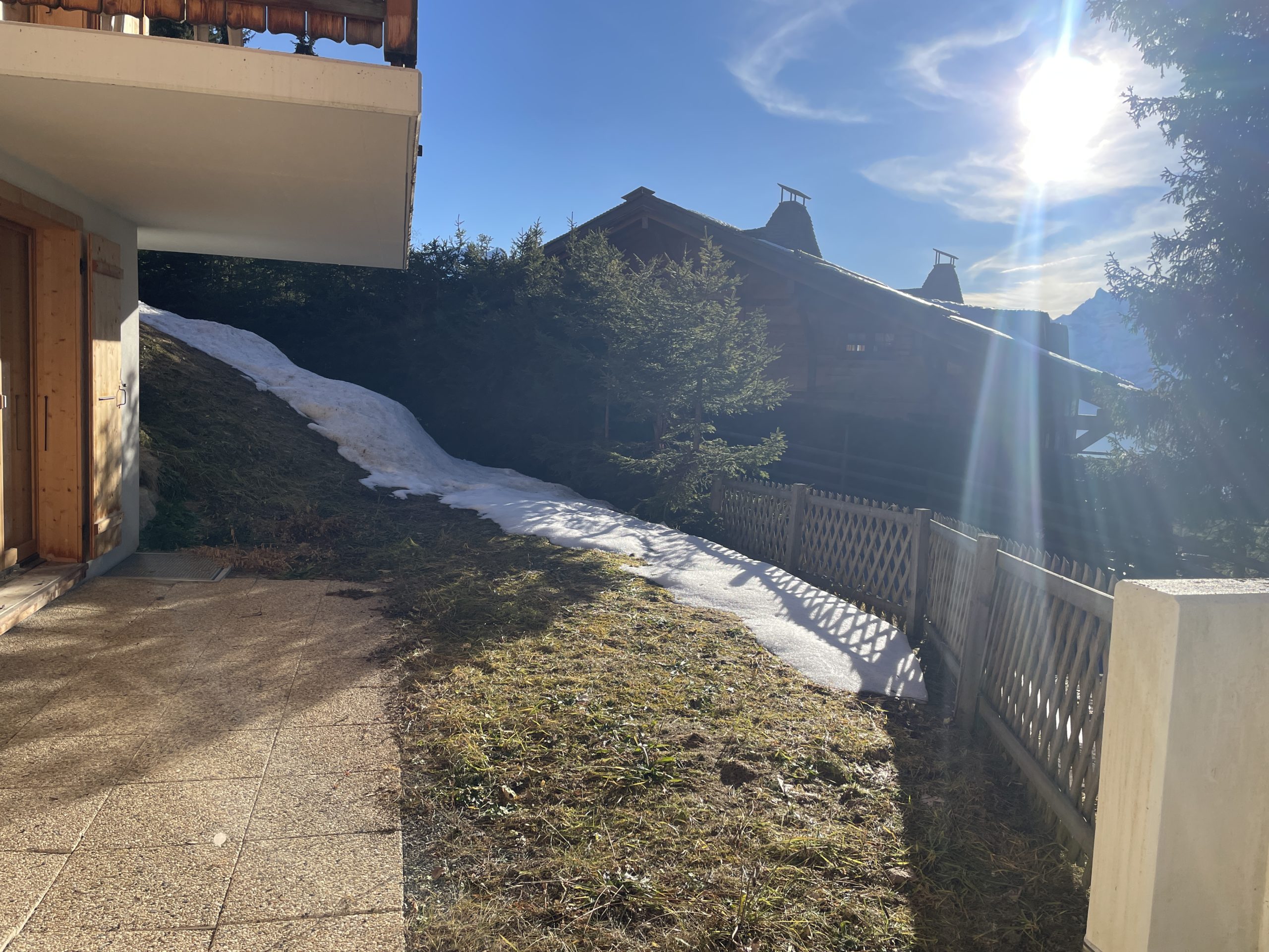 Sonnige Außenansicht mit Terrasse und verschneitem Hang