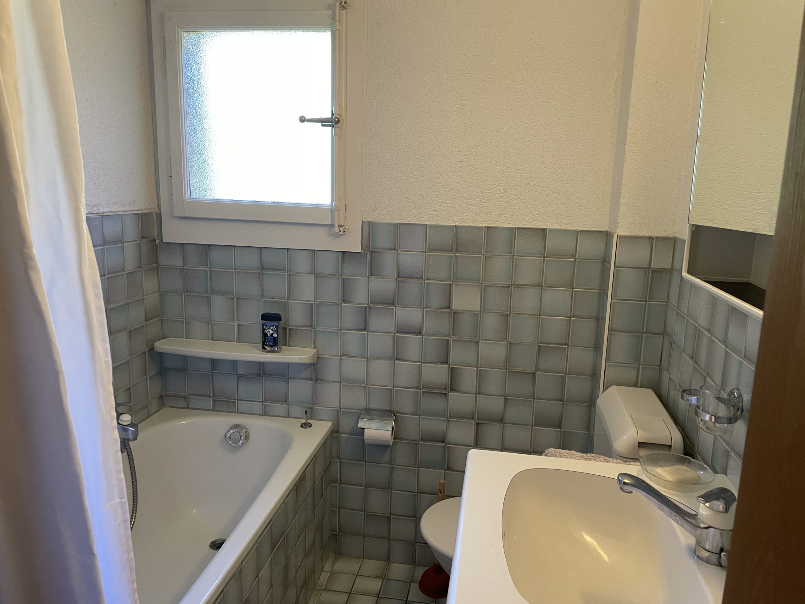 Kleines Badezimmer mit Badewanne, Waschbecken und WC
