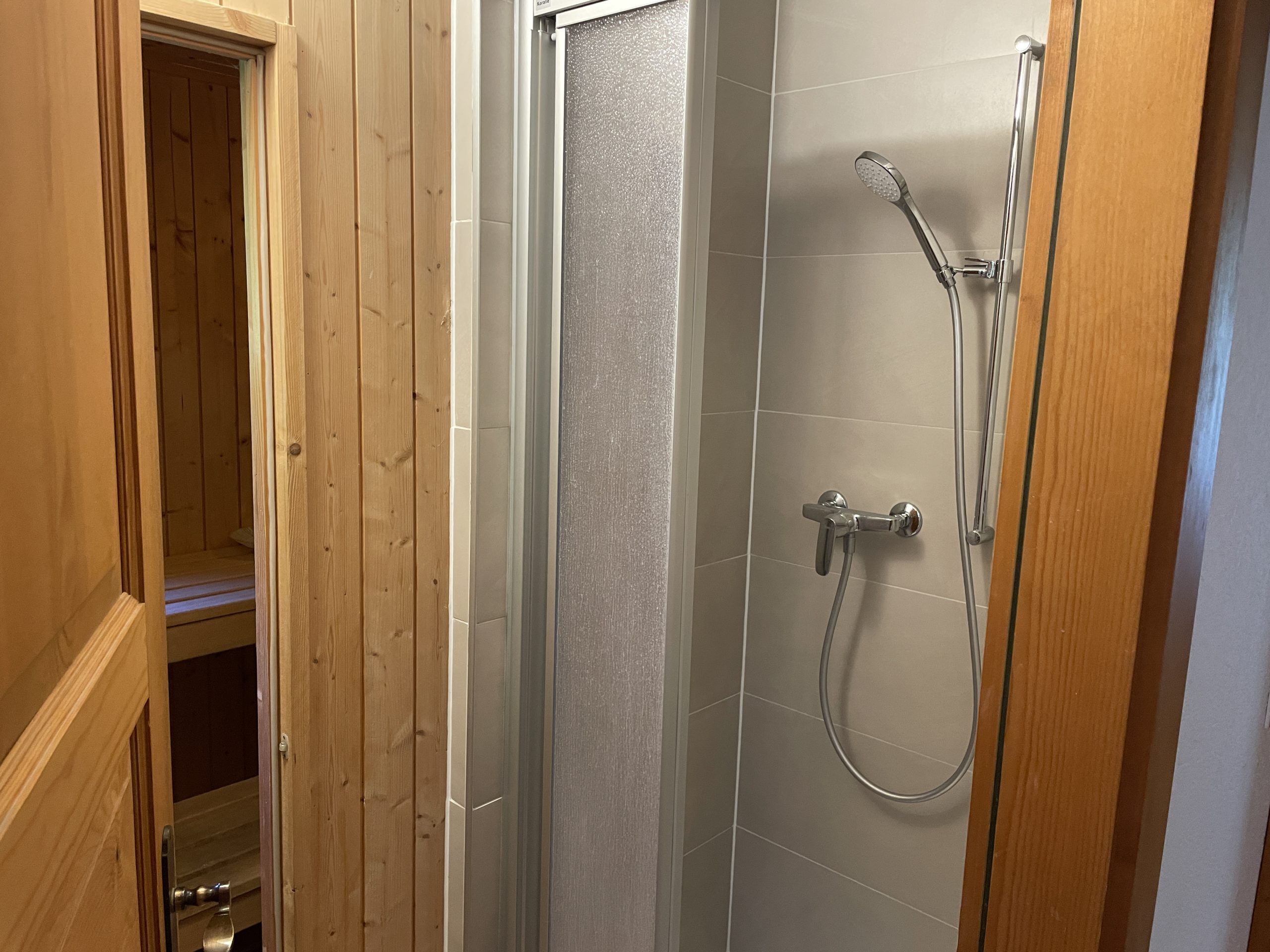 Dusche neben Holzverkleidung und Sauna