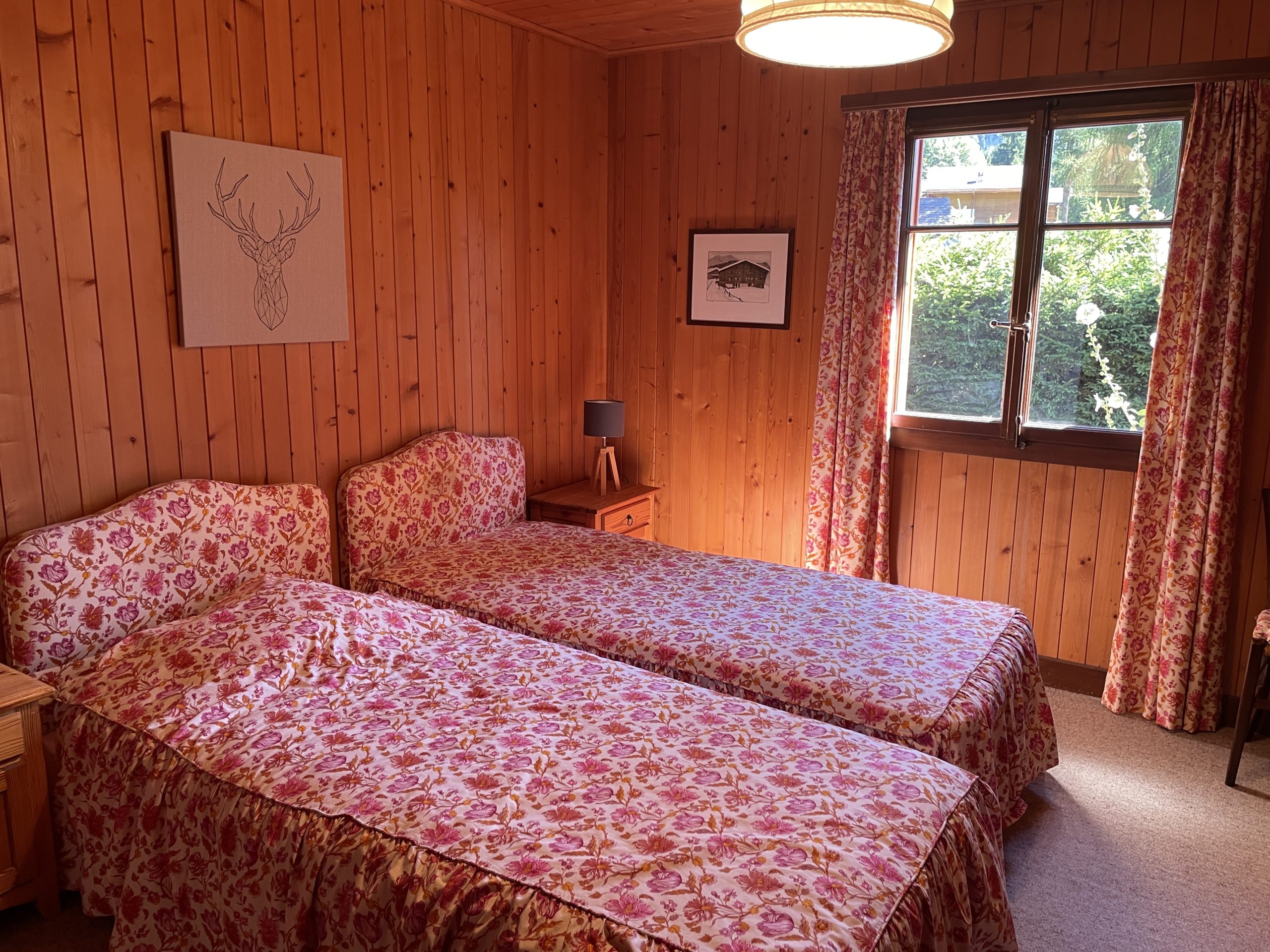 Gemütliches Schlafzimmer mit Holzvertäfelung und floralen Textilien