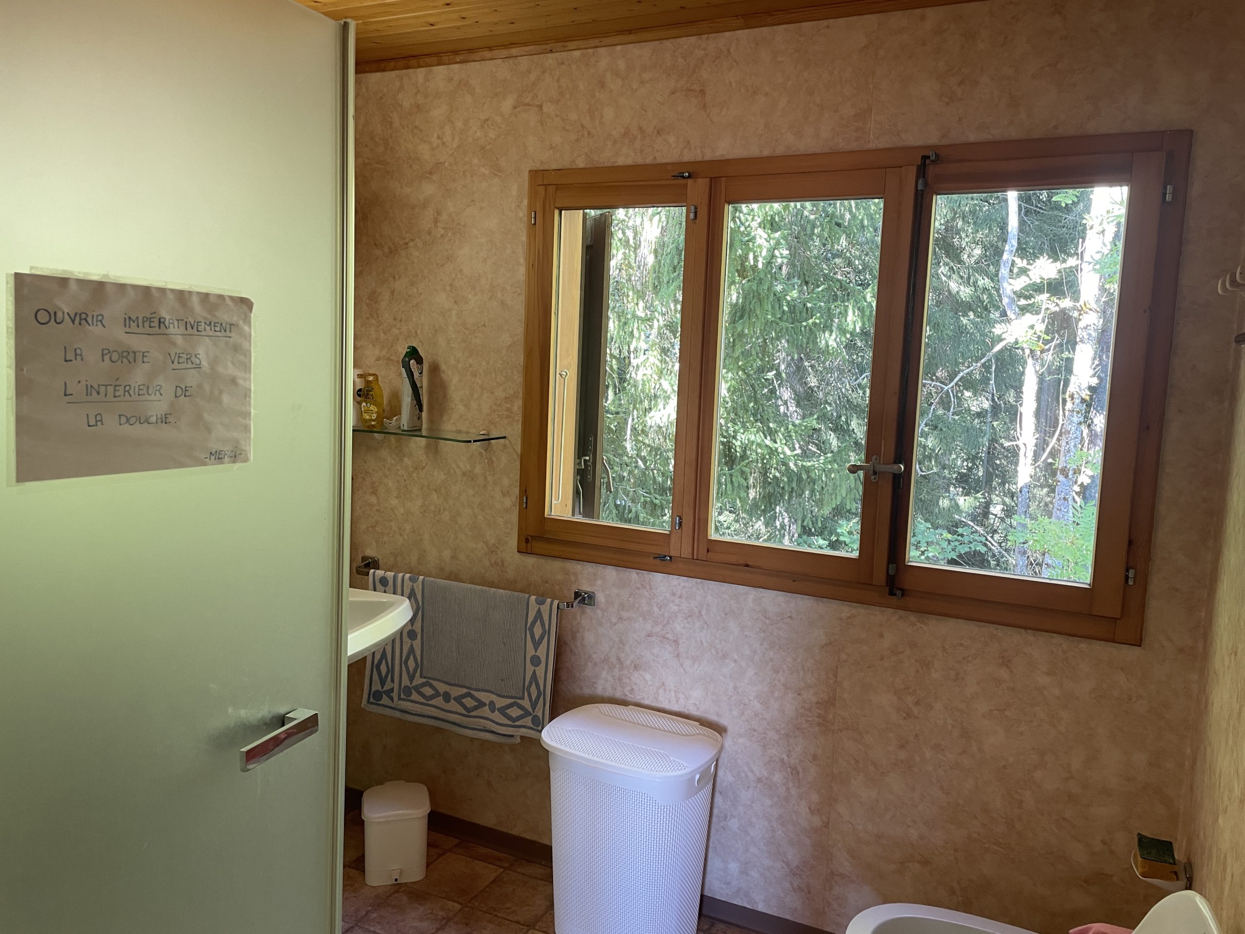 Badezimmer mit Holzfenster und Waldblick