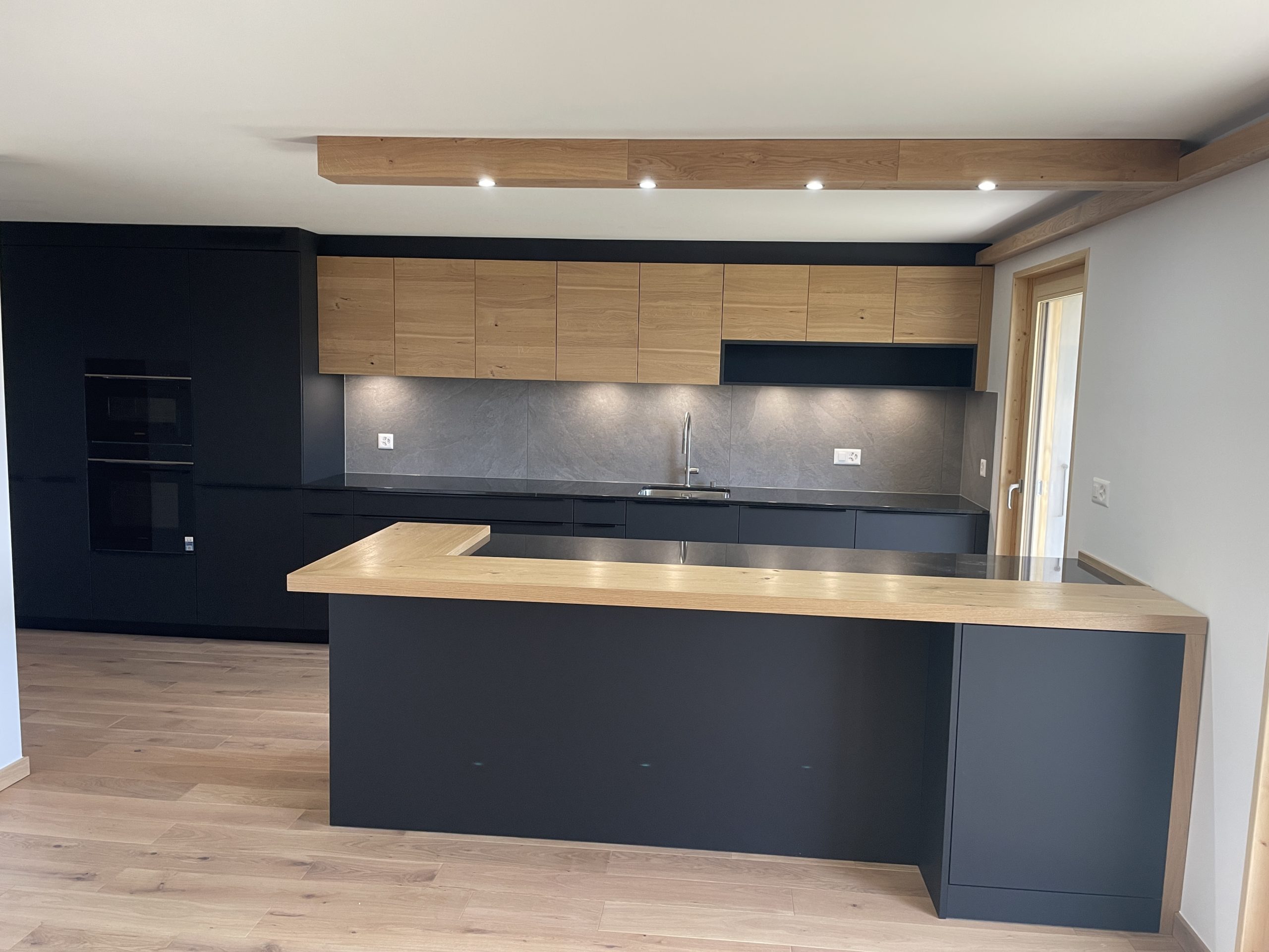 Moderne offene Küche mit dunklen Fronten und Holzdetails
