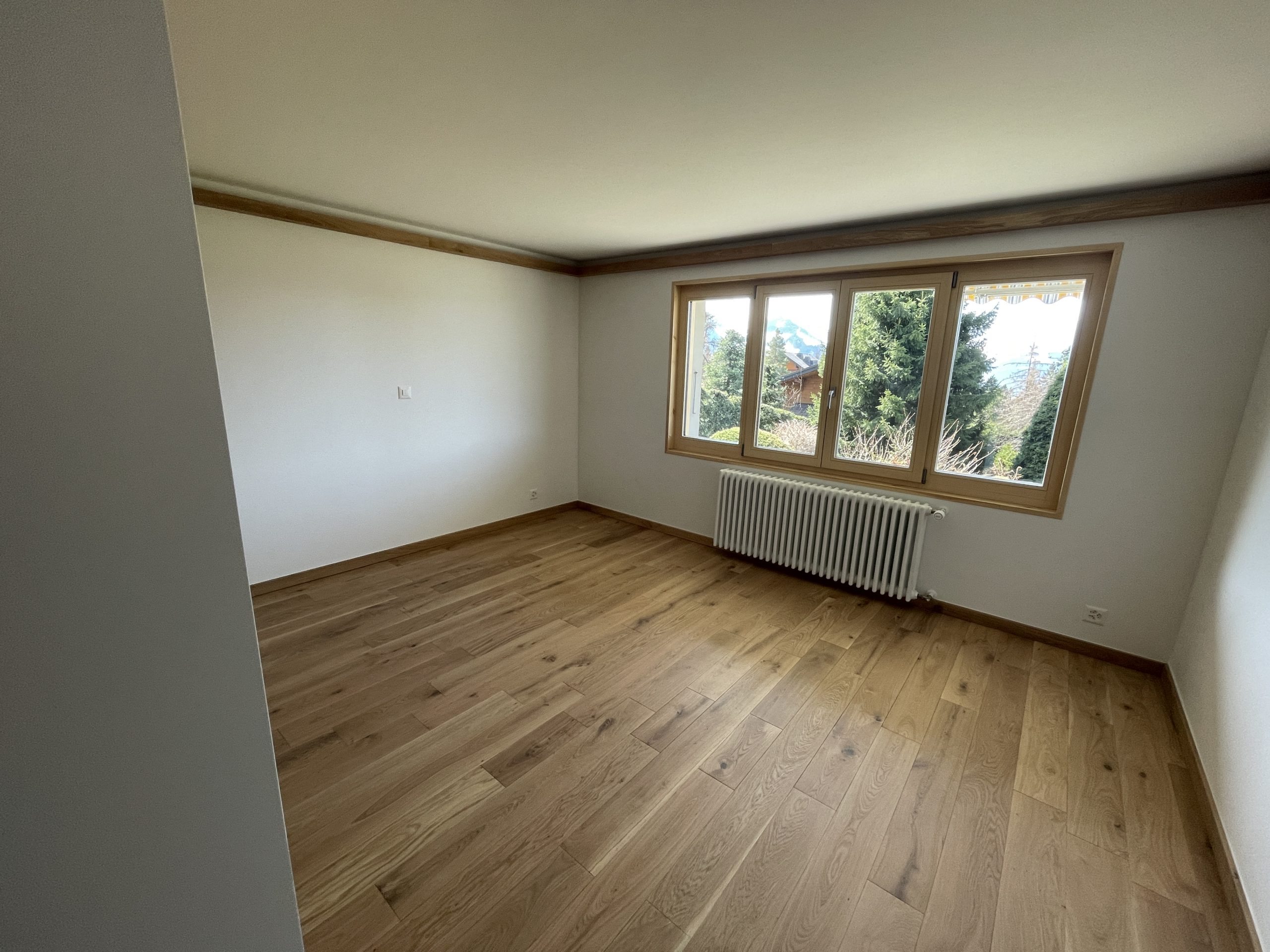 Leeres, helles Zimmer mit Holzfußboden