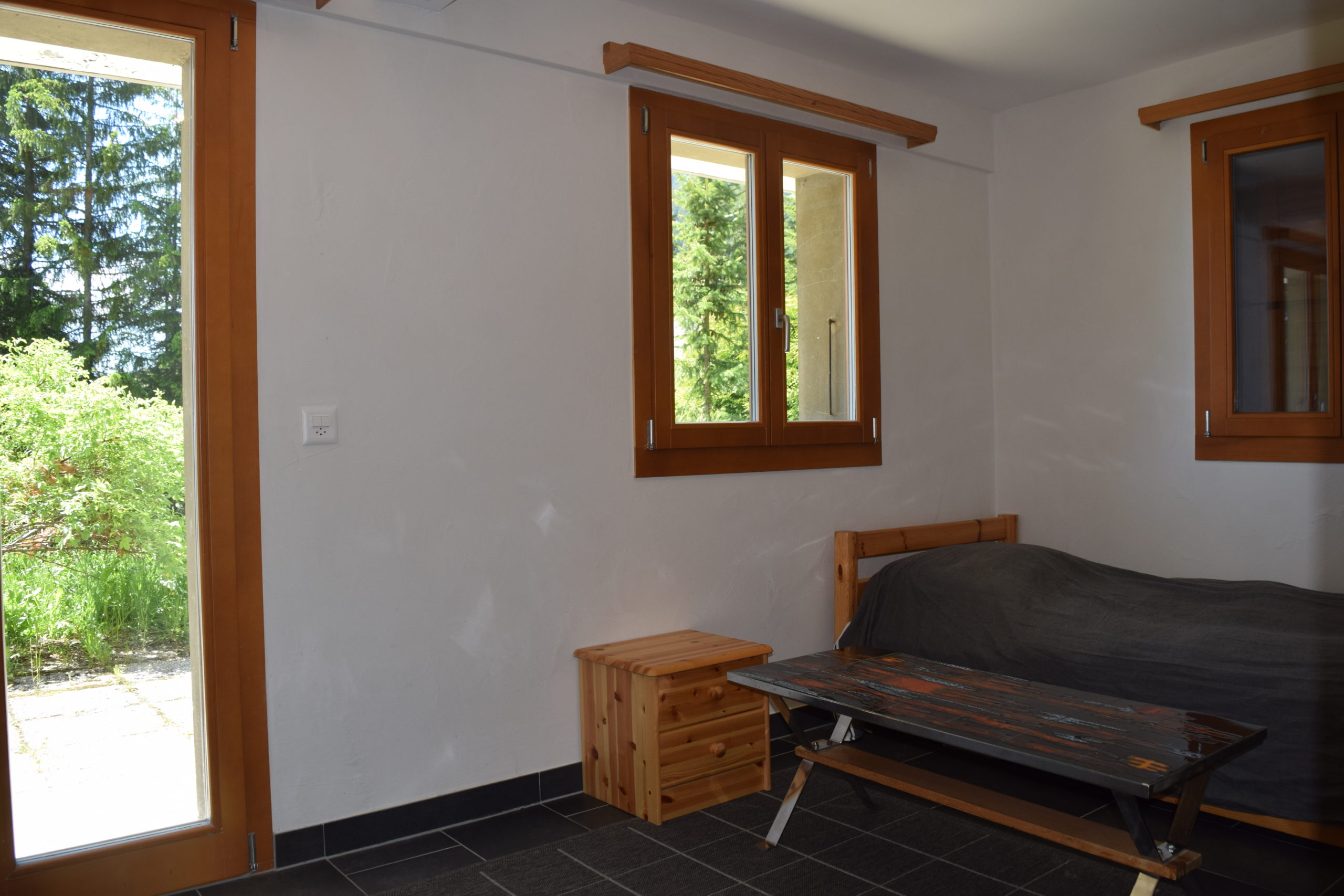 Helles Zimmer mit Holzfenstern und Blick ins Grüne
