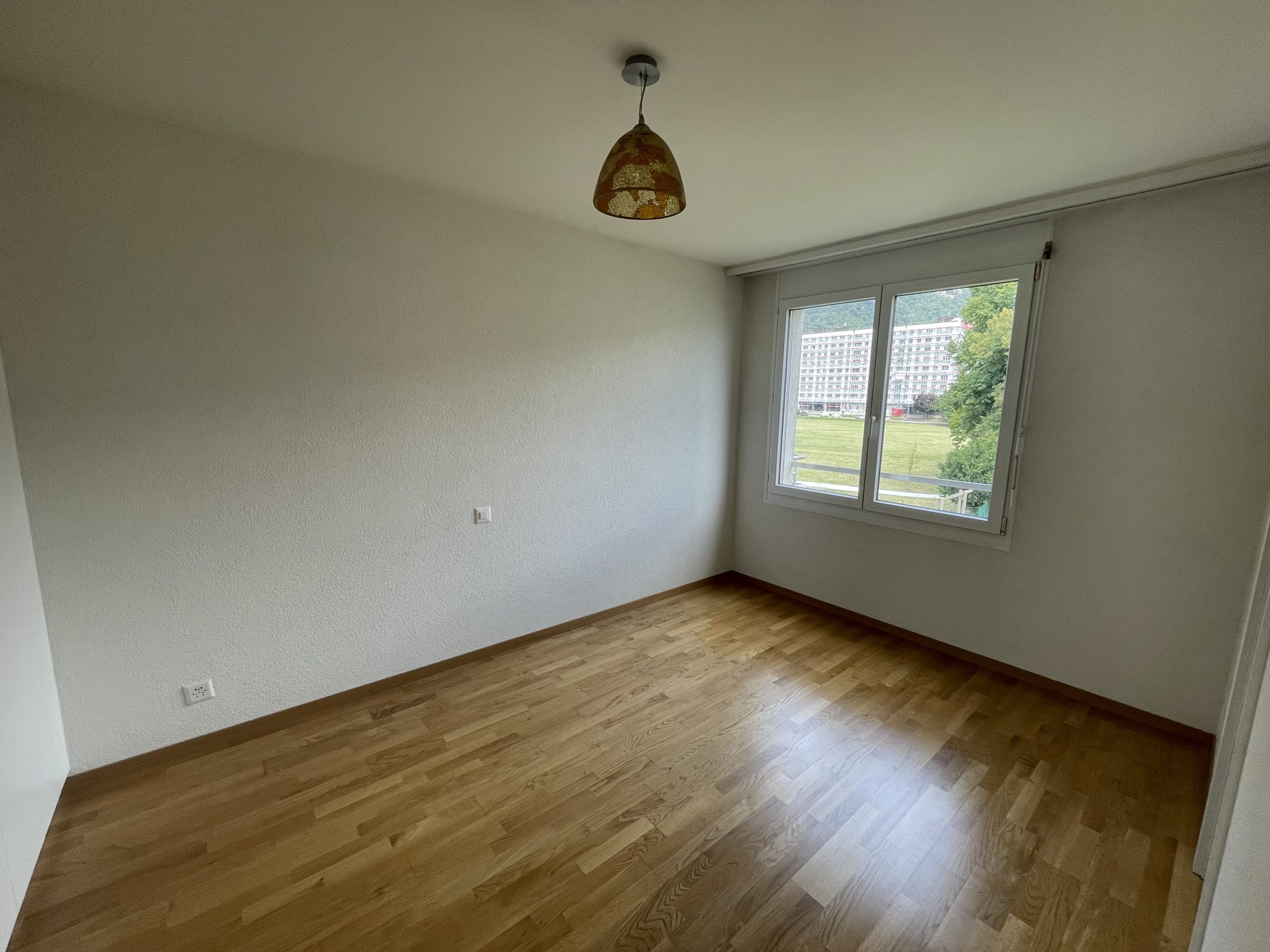 Leerer Wohnraum mit Parkett und Fensterblick