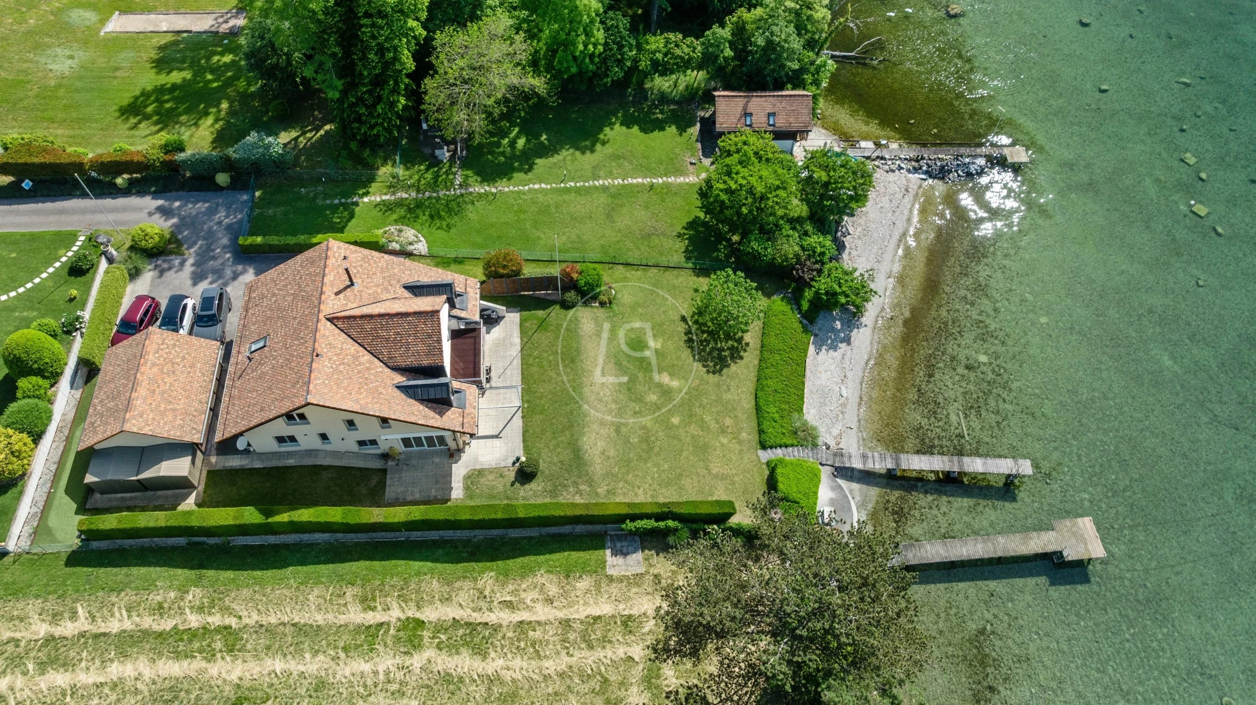 Luftaufnahme eines Seegrundstücks mit Haus, Garten und Steg