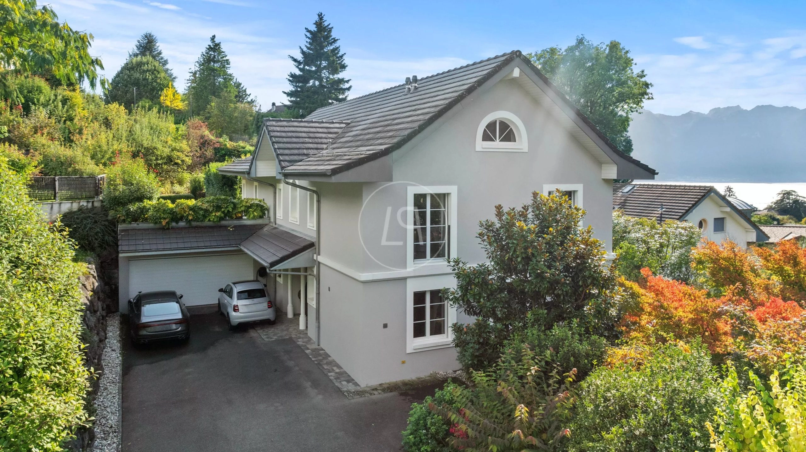 Außenansicht eines gepflegten Hauses am Hang mit Garage und Seeblick