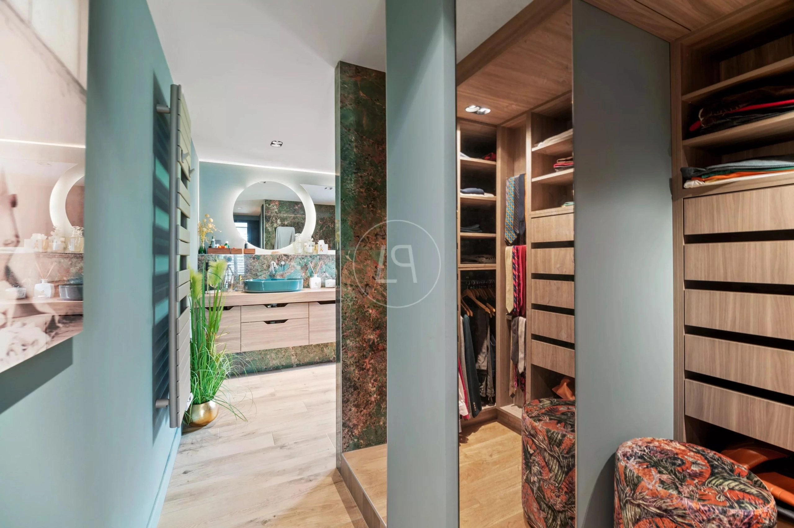 Begehbarer Kleiderschrank mit Ankleide und Bad im Hintergrund