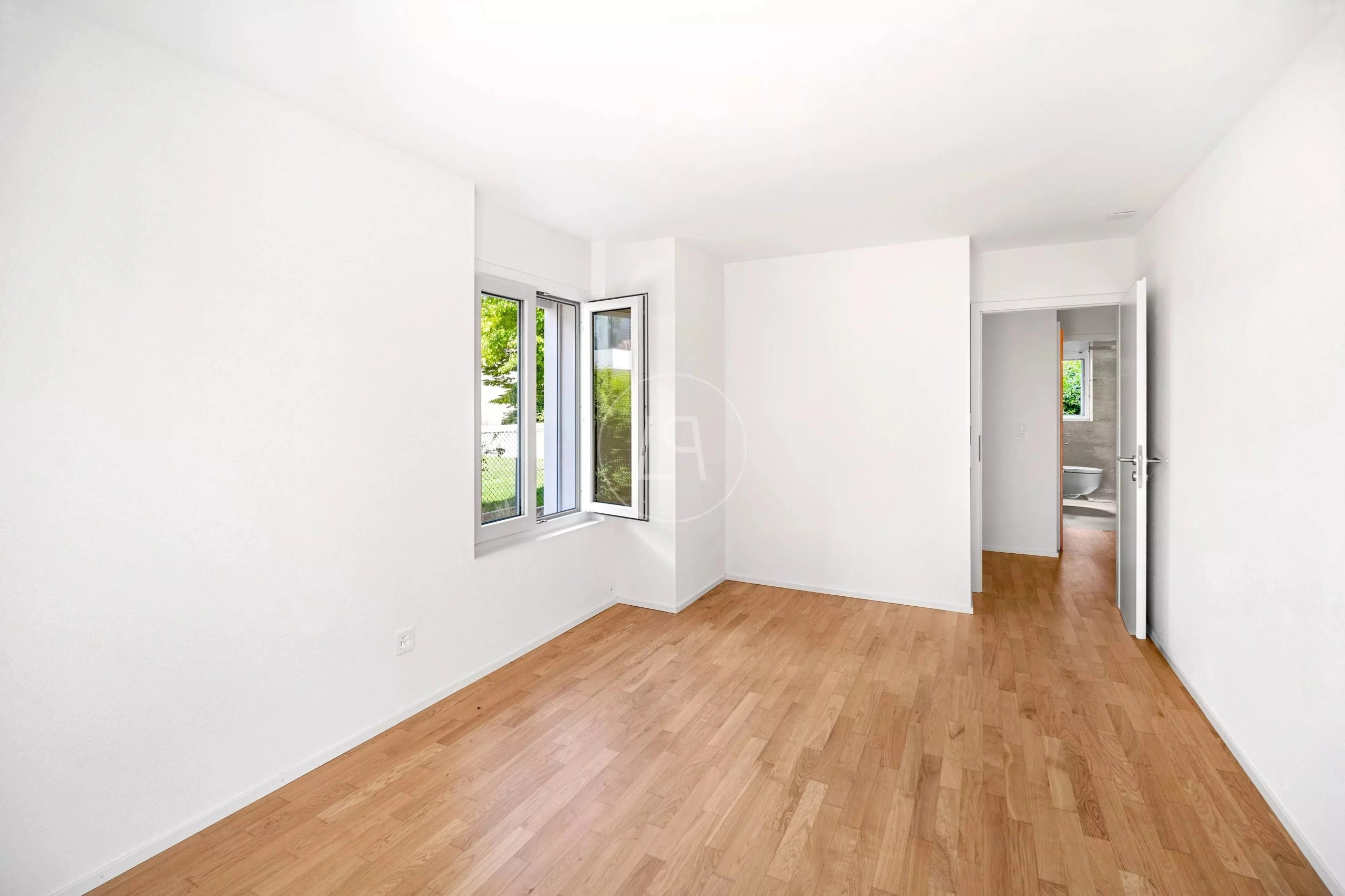 Heller leerer Raum mit Parkett und Fenster zum Garten