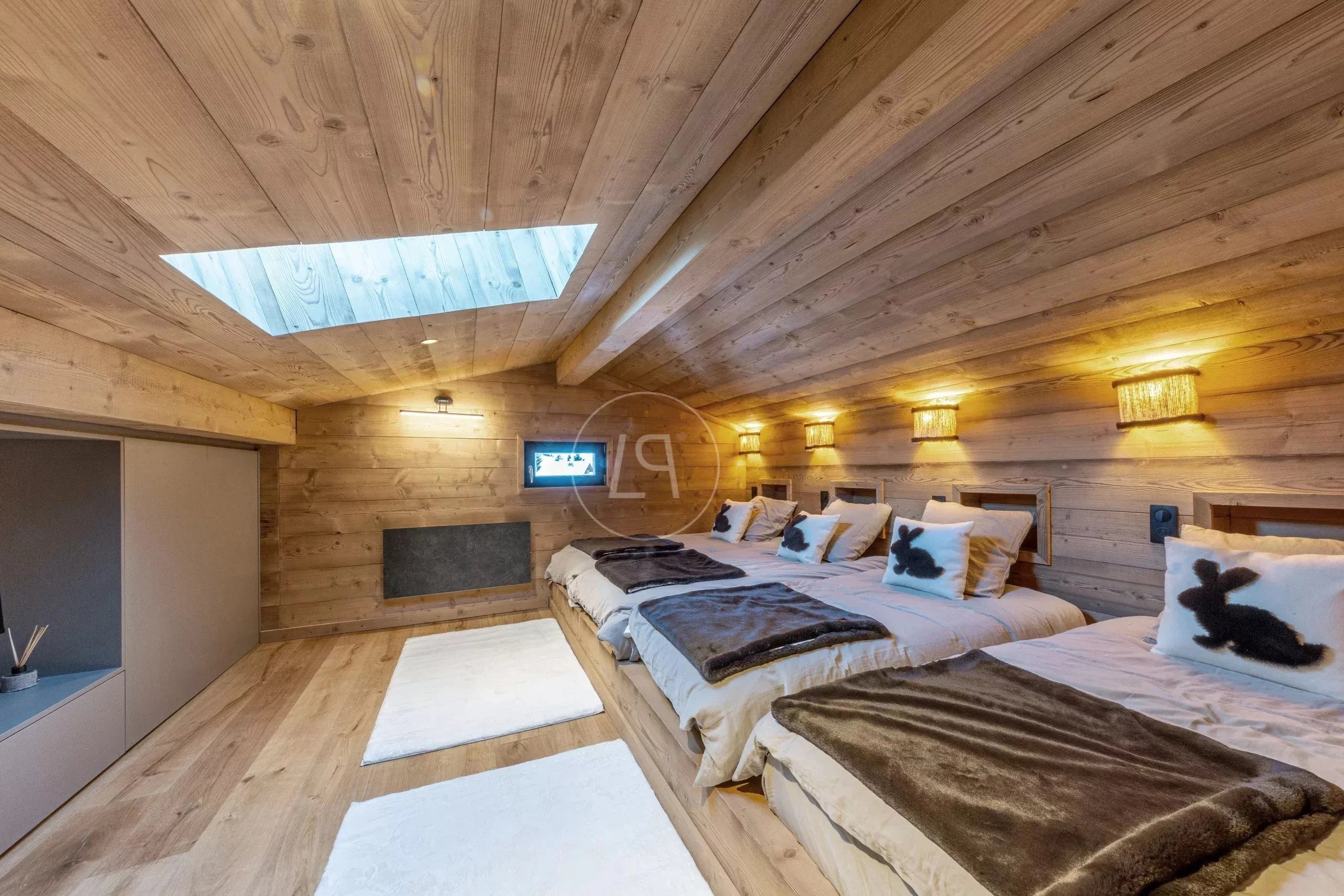Gemütliches Holz-Schlafzimmer mit mehreren Betten und Dachfenster