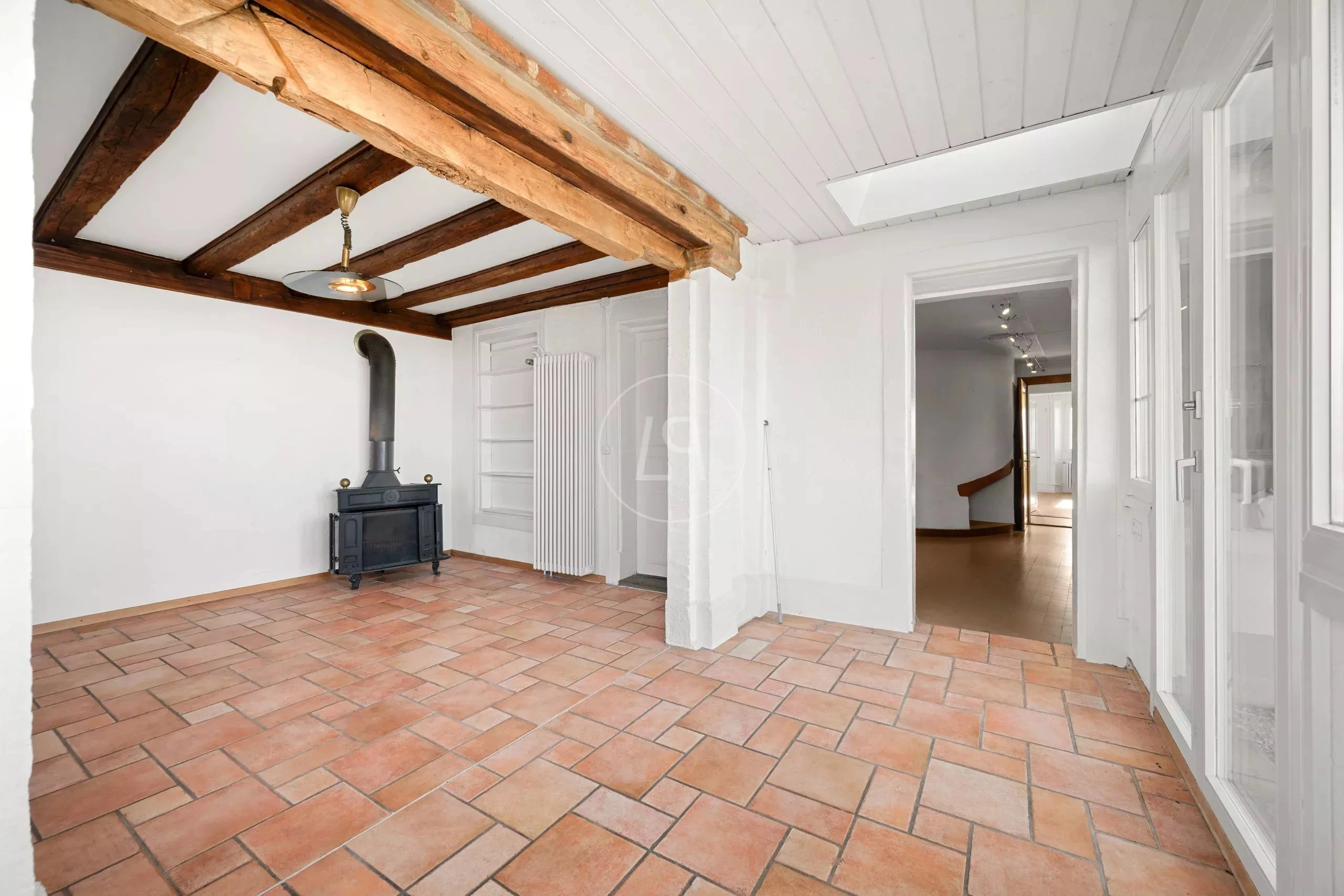 Heller Raum mit Terrakottafliesen und sichtbarem Kaminofen
